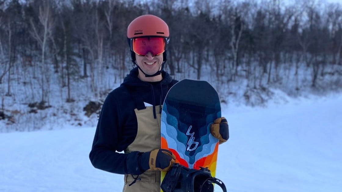 Man stands with a snowboard.