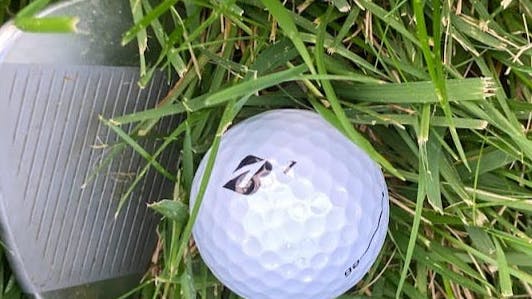 The Bridgestone 2021 E6 Golf Ball in front of a golf club. 