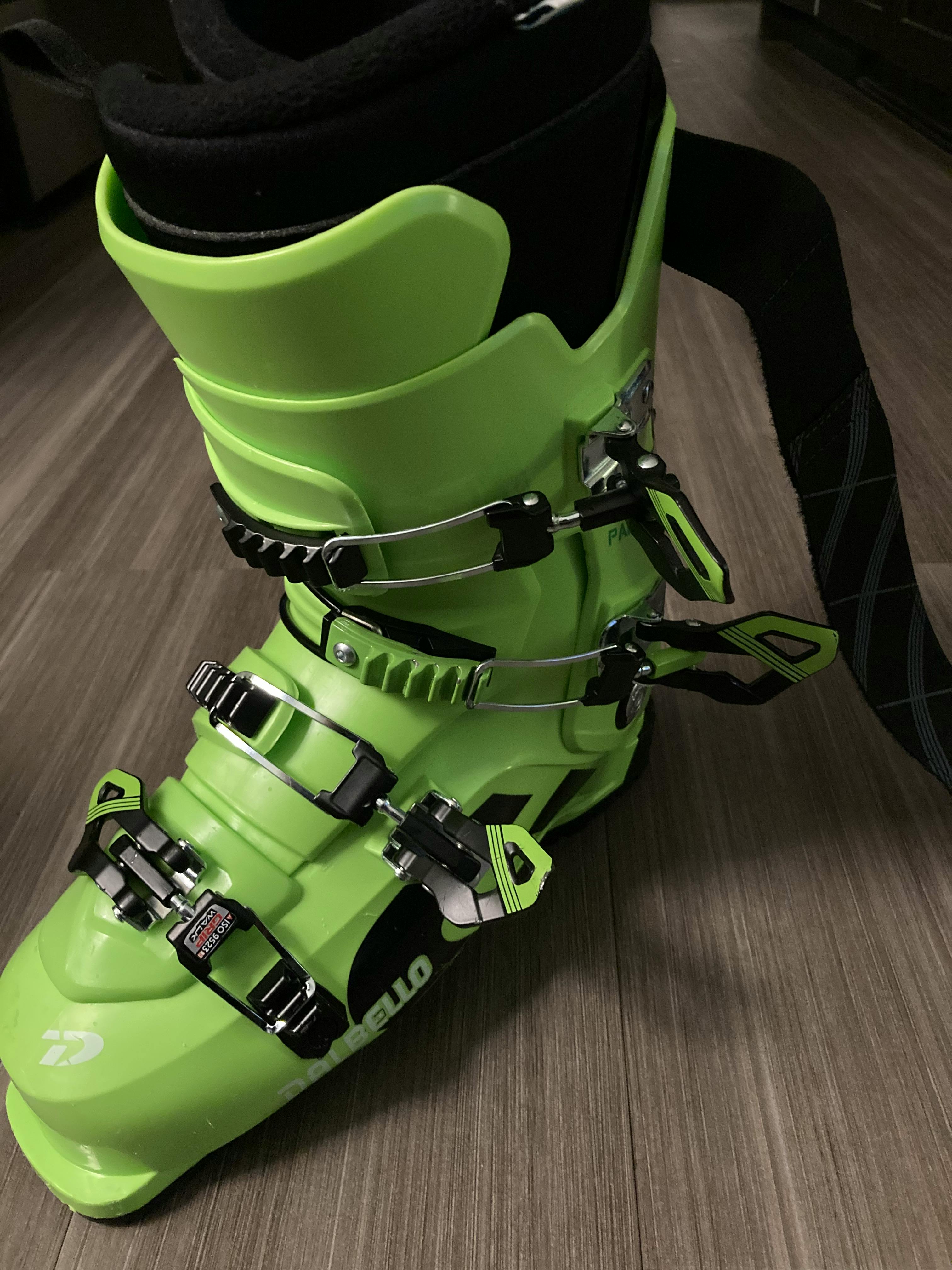 A lime green and black ski boot getting tried on indoors