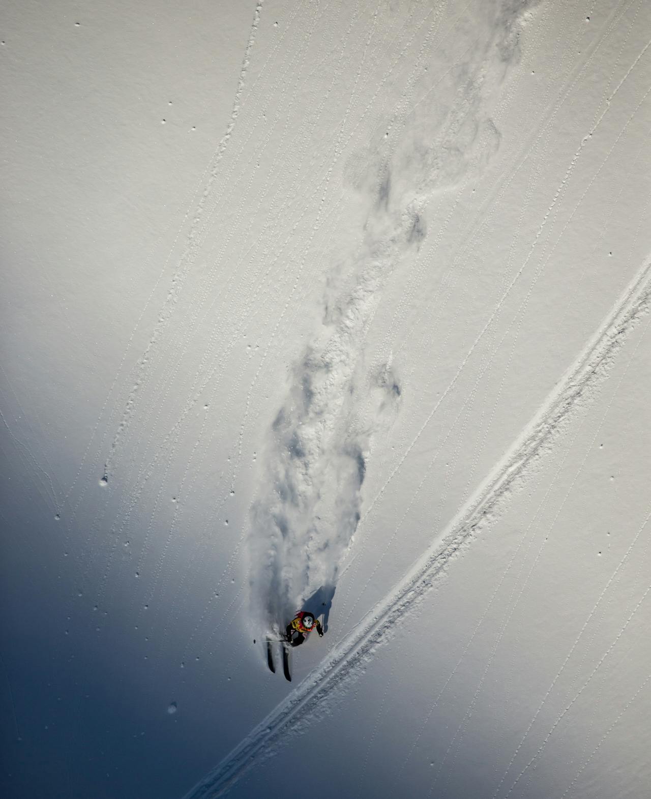 One of the female competitors skis down an untouched face. The photo is taken from above her. 