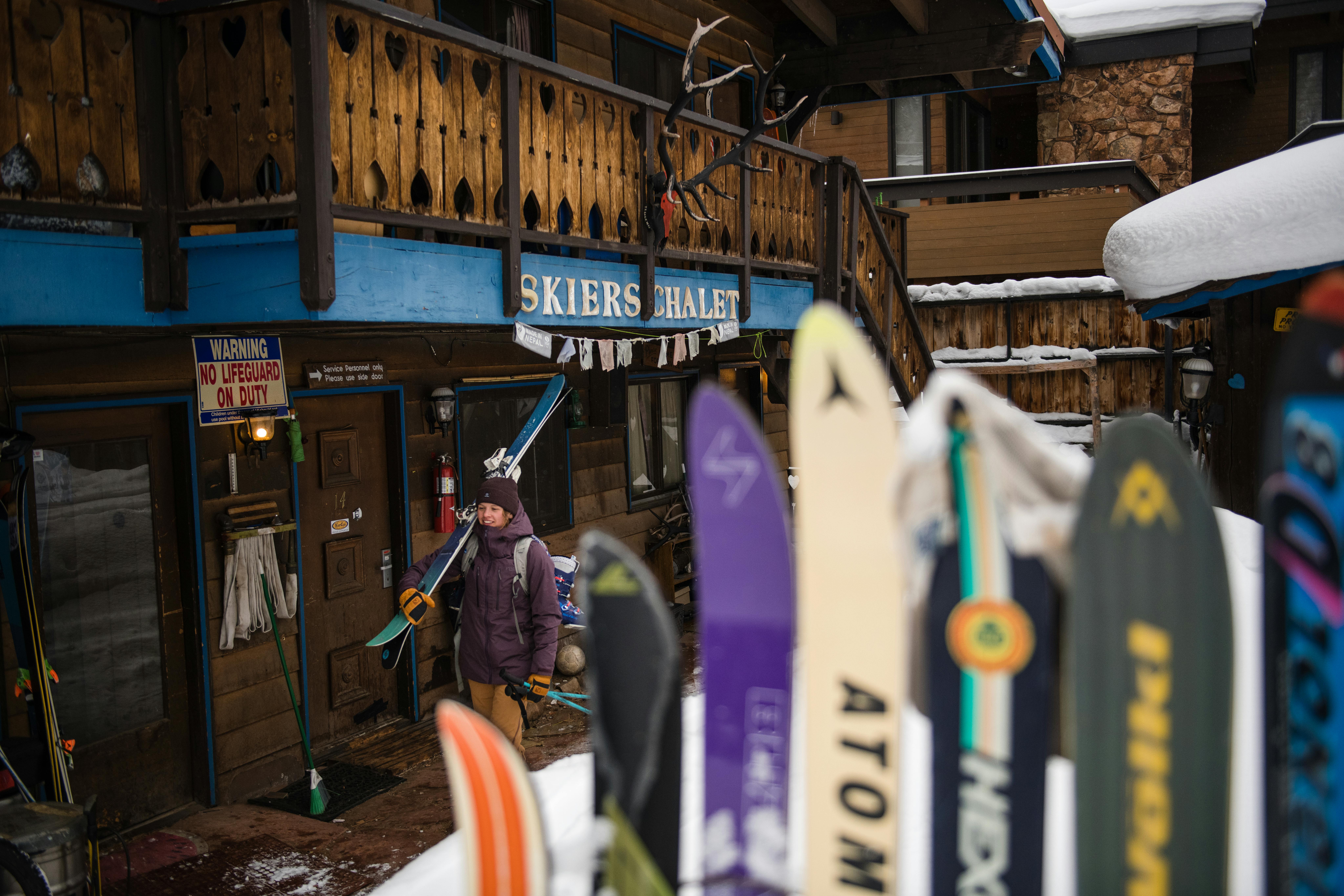 A woman walking carrying skis in a ski town