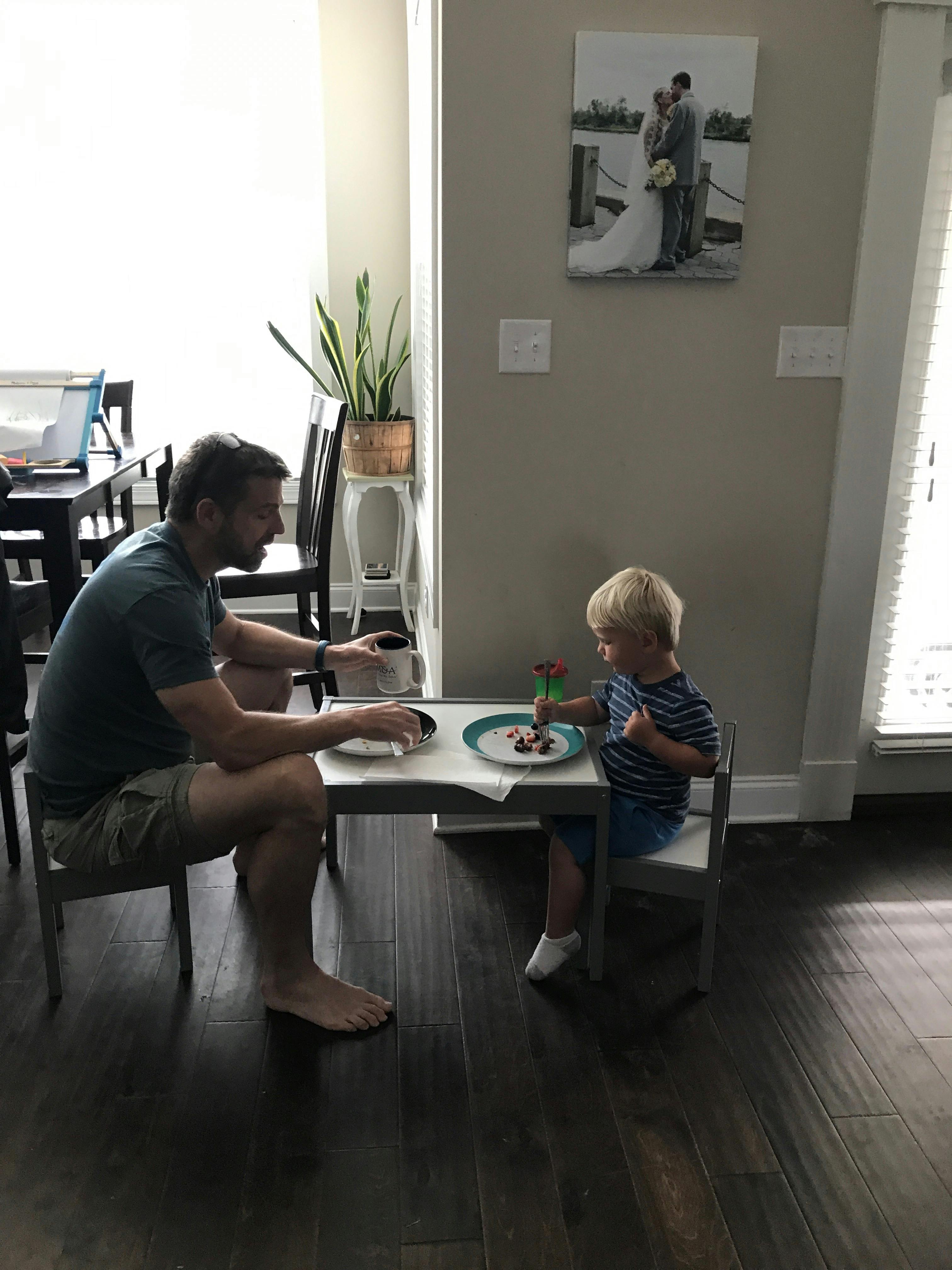 A grandpa and kid sit at a small table.