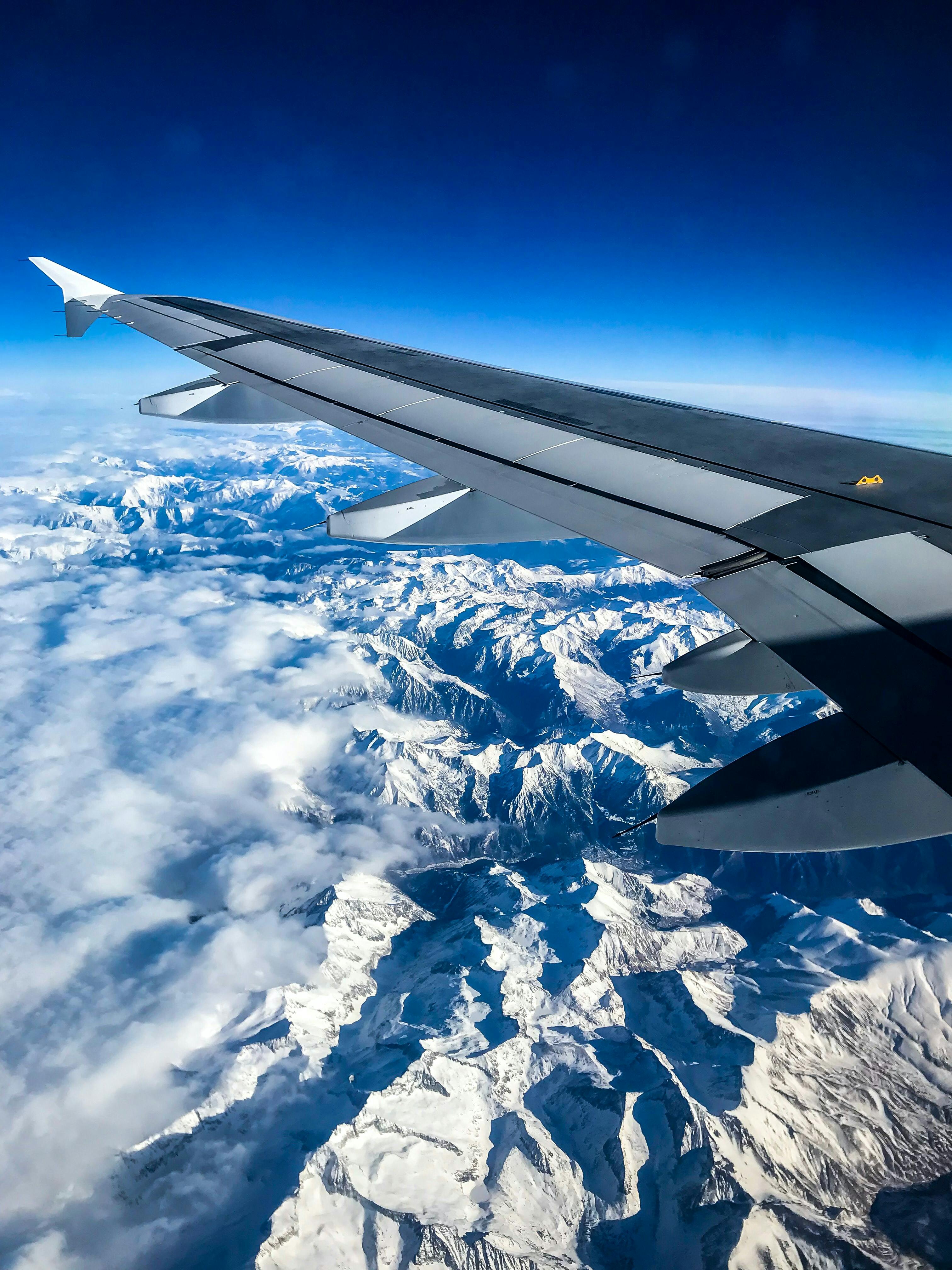 A view out of a plane window looking down at snowy mountains.