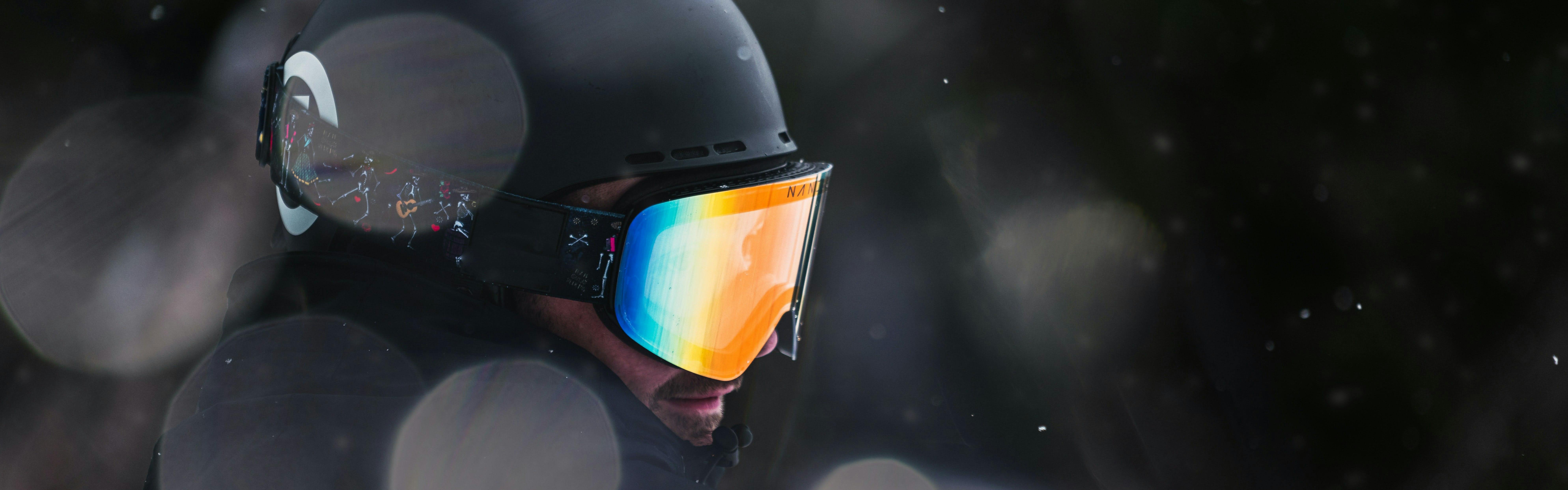 A skier or snowboarder wears a helmet and goggles while snow falls around them.