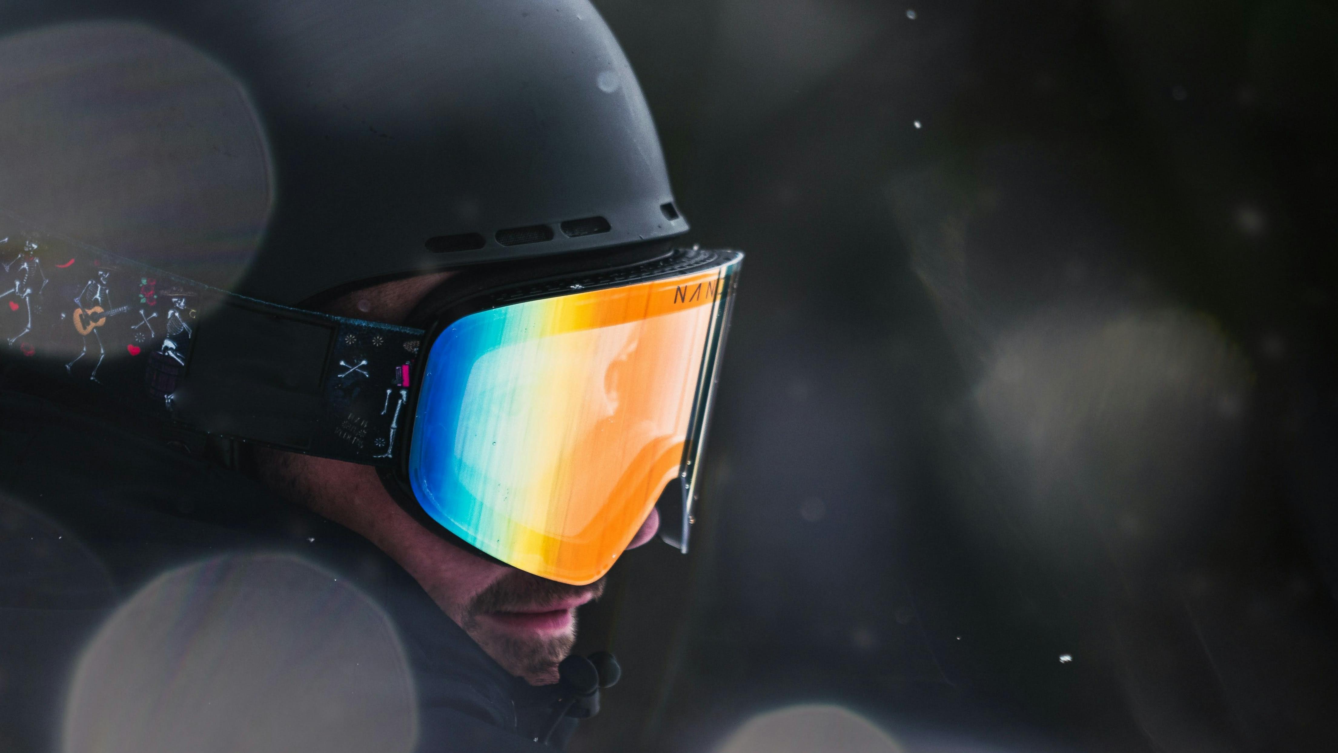 A skier or snowboarder wears a helmet and goggles while snow falls around them.