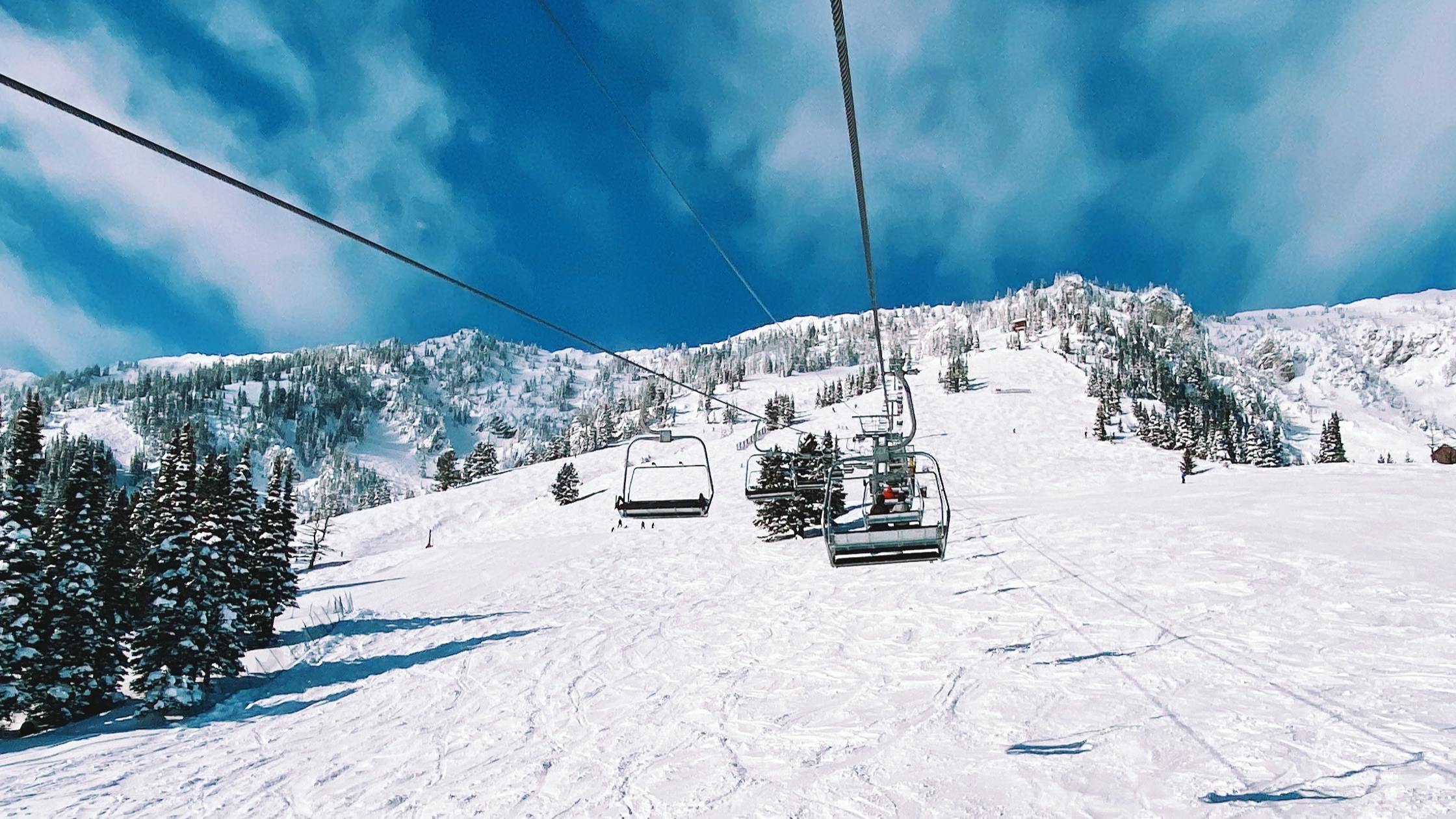View of the chairlift and snowy slope below from one of the chairs