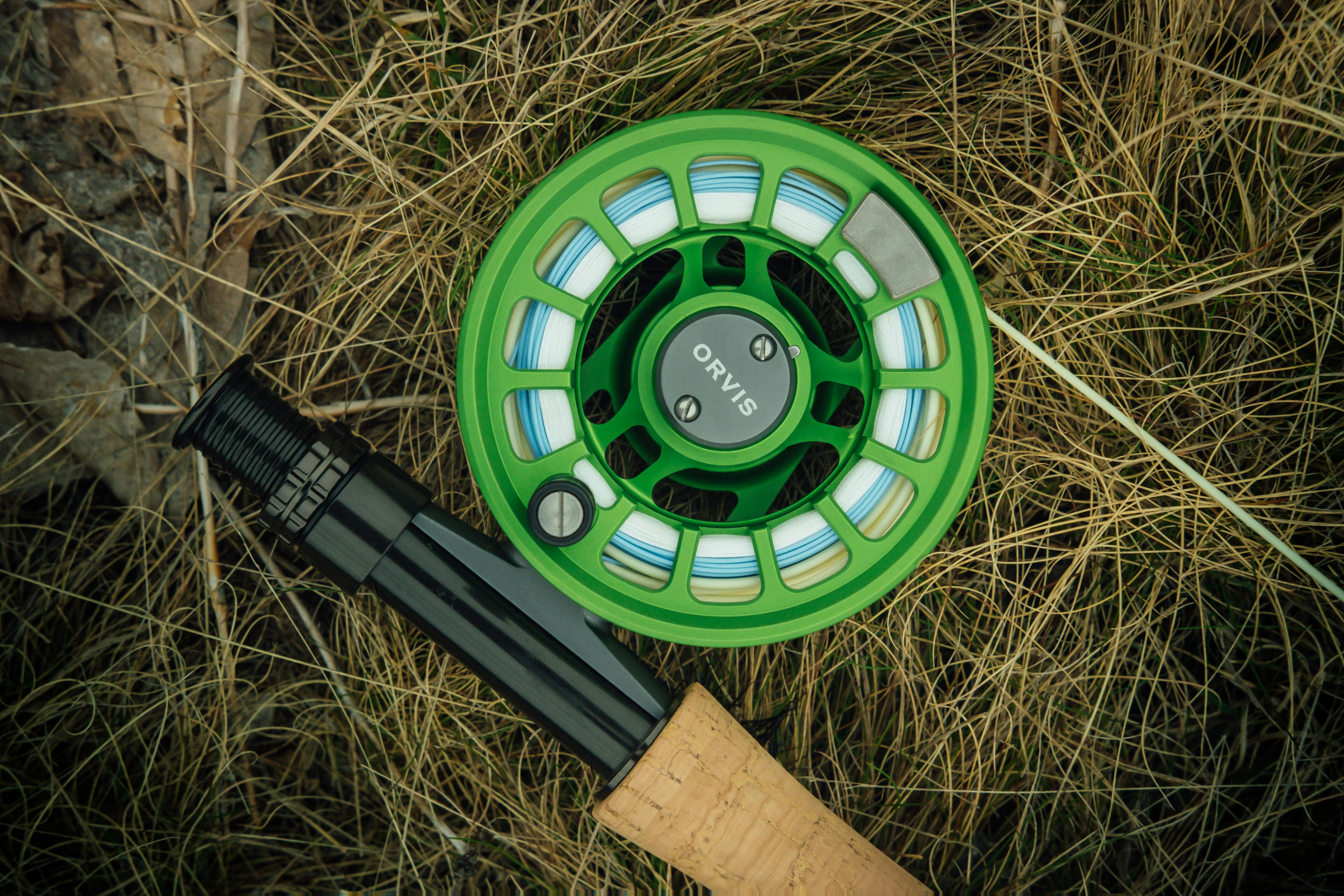A green fly reel attached to a rod. 