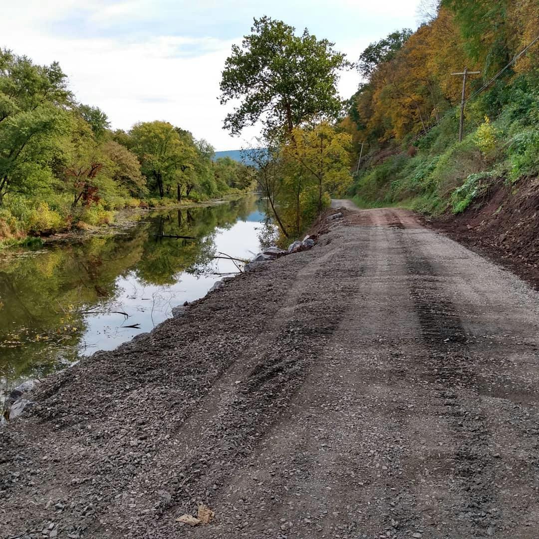 A gravel trail with a river along the side of it. 