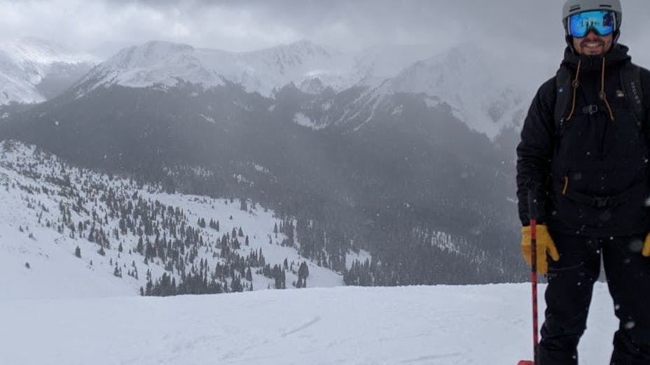 A skier standing at the top of a snowy run.