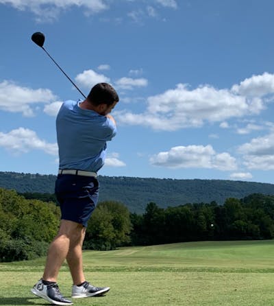 A man taking a swing with a golf club at a Srixon Soft Feel 12 Golf Ball.
