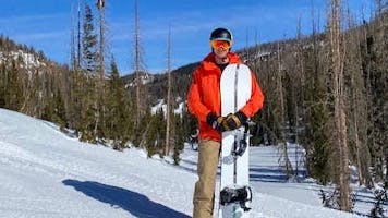 A man holding a snowboard mounted with the Burton Malavita Snowboard Bindings.