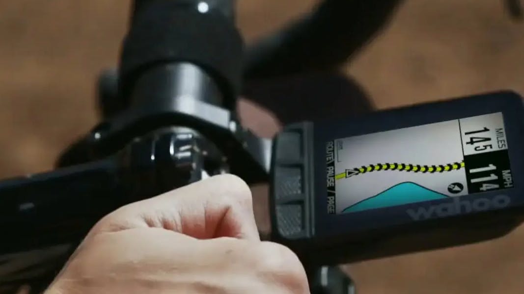 A cyclist rides with a Wahoo Elemnt bike computer on their handlebars. 