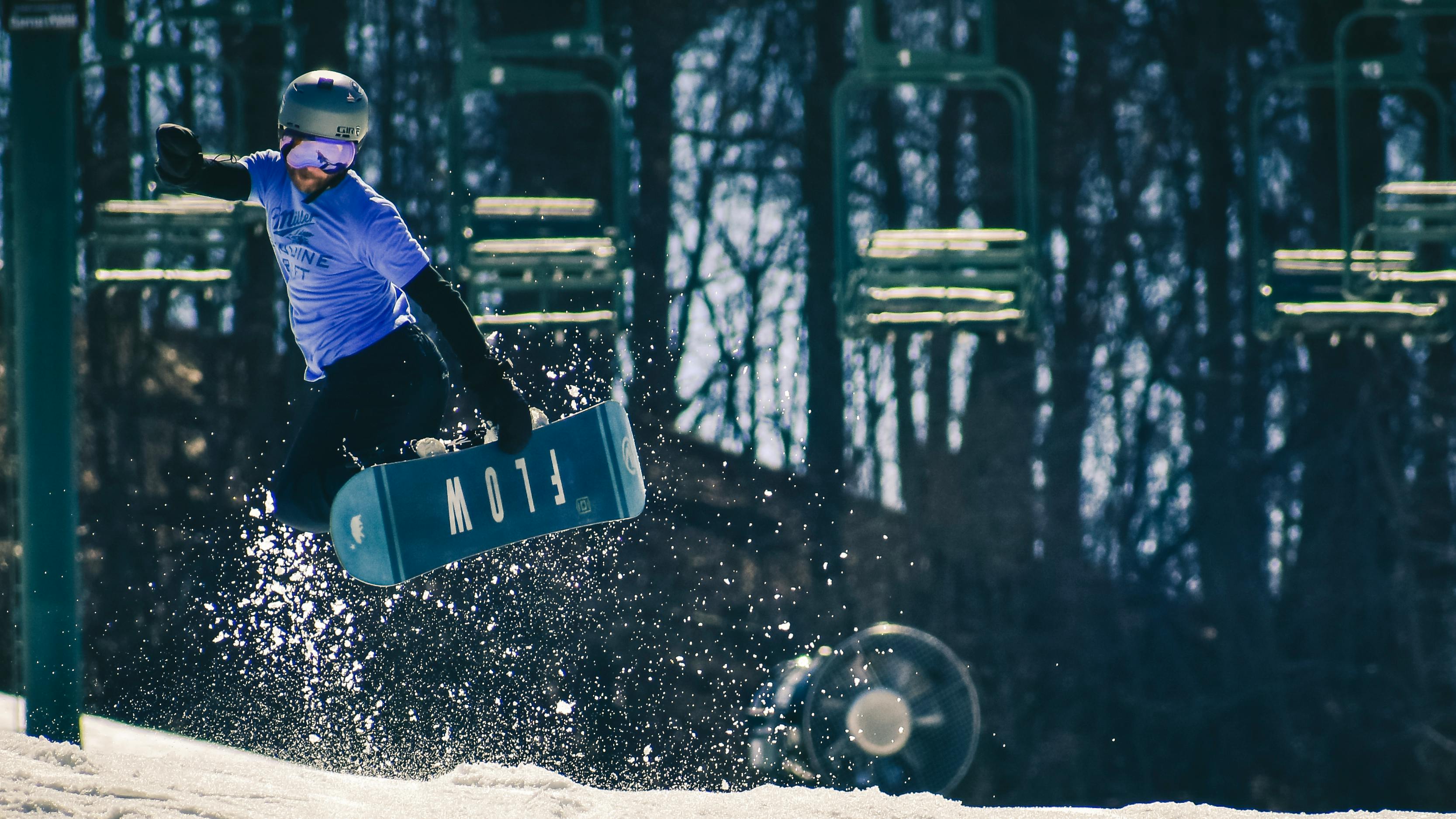 A man in a purple shirt executes a trick on a snowboard