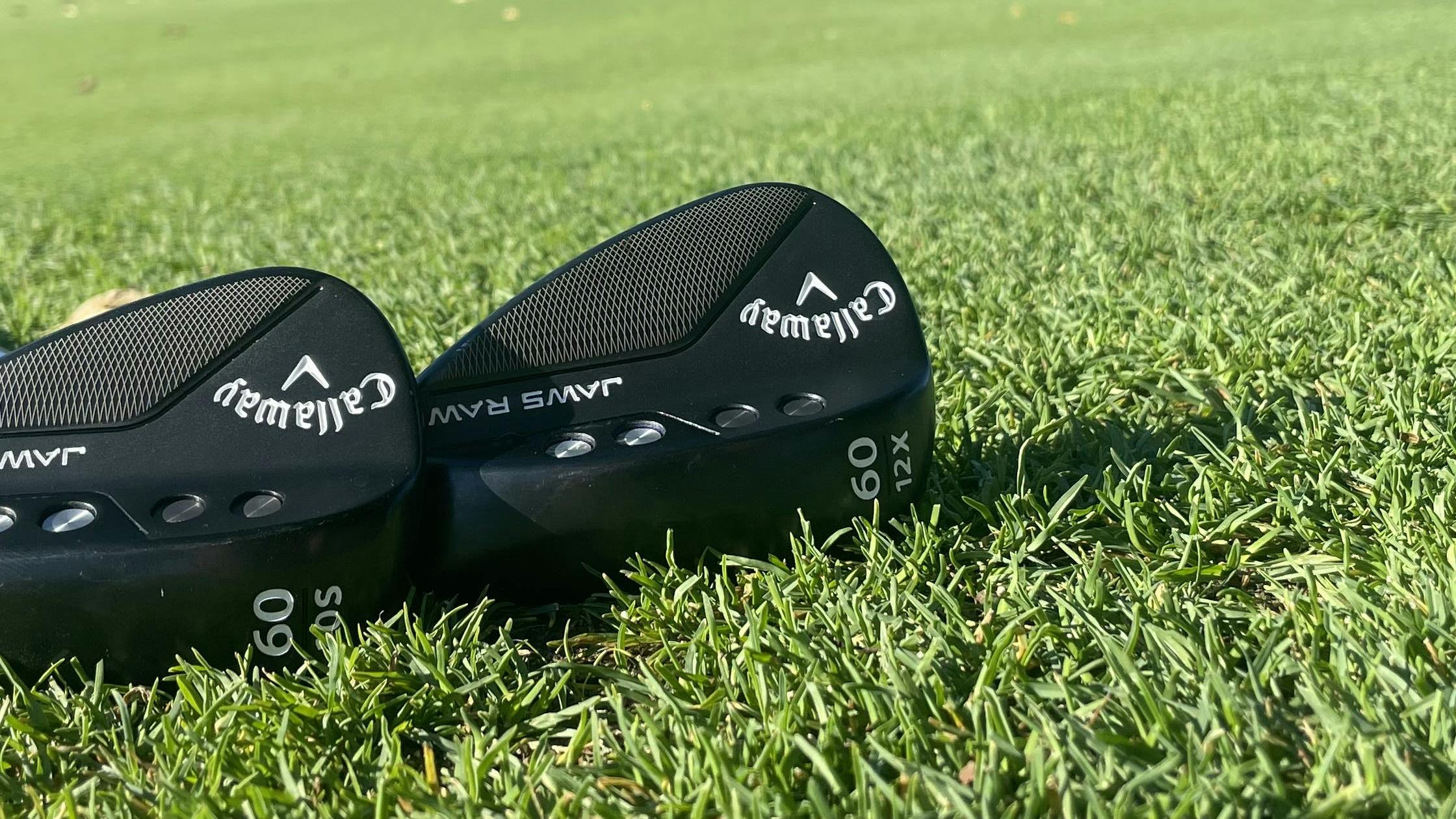 Two Callaway Golf Jaws Raw Plasma Black Wedges lying in the grass.