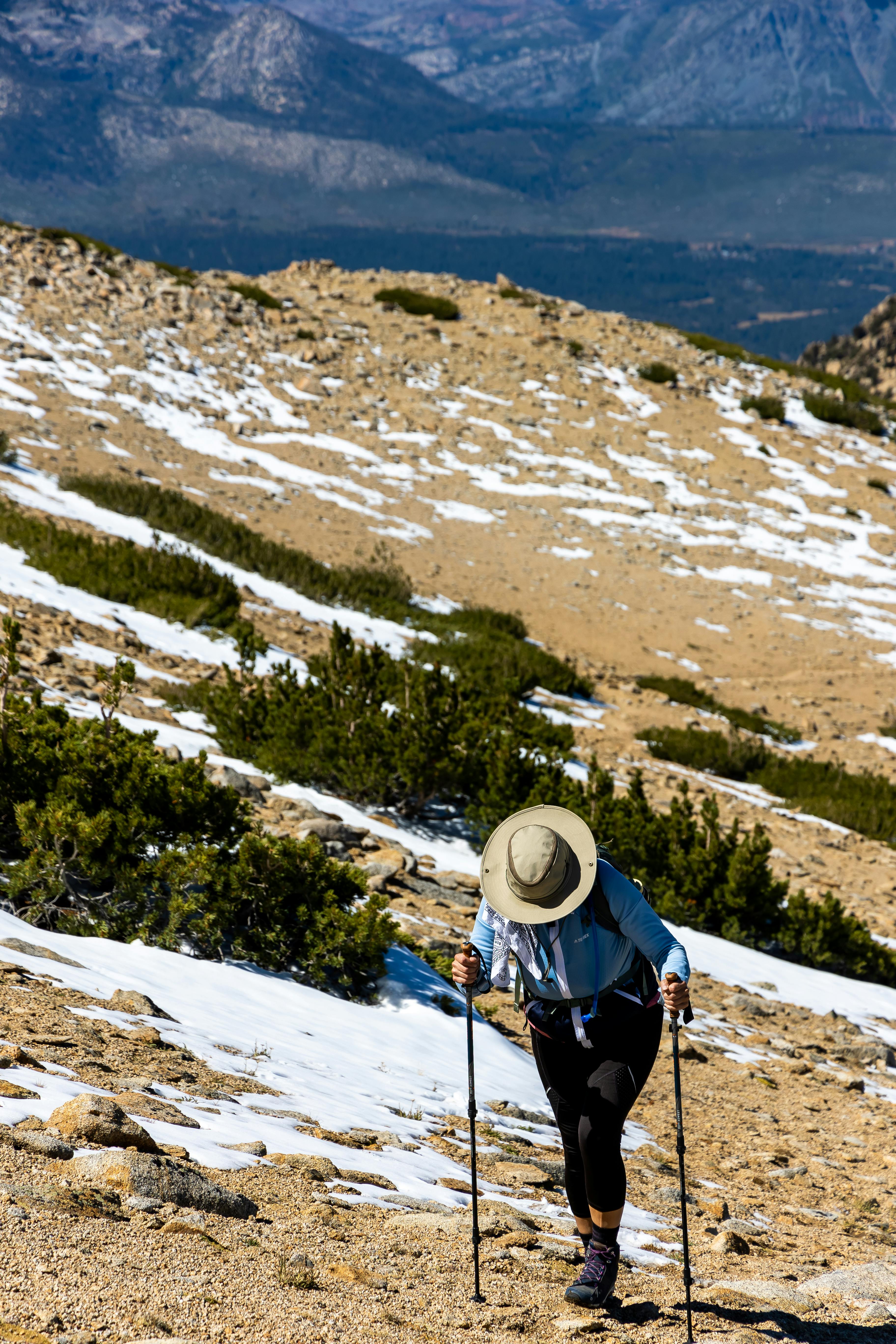 A hiker hiking with the Leki Legacy Lite Trekking Poles. There are mountains in the background. 