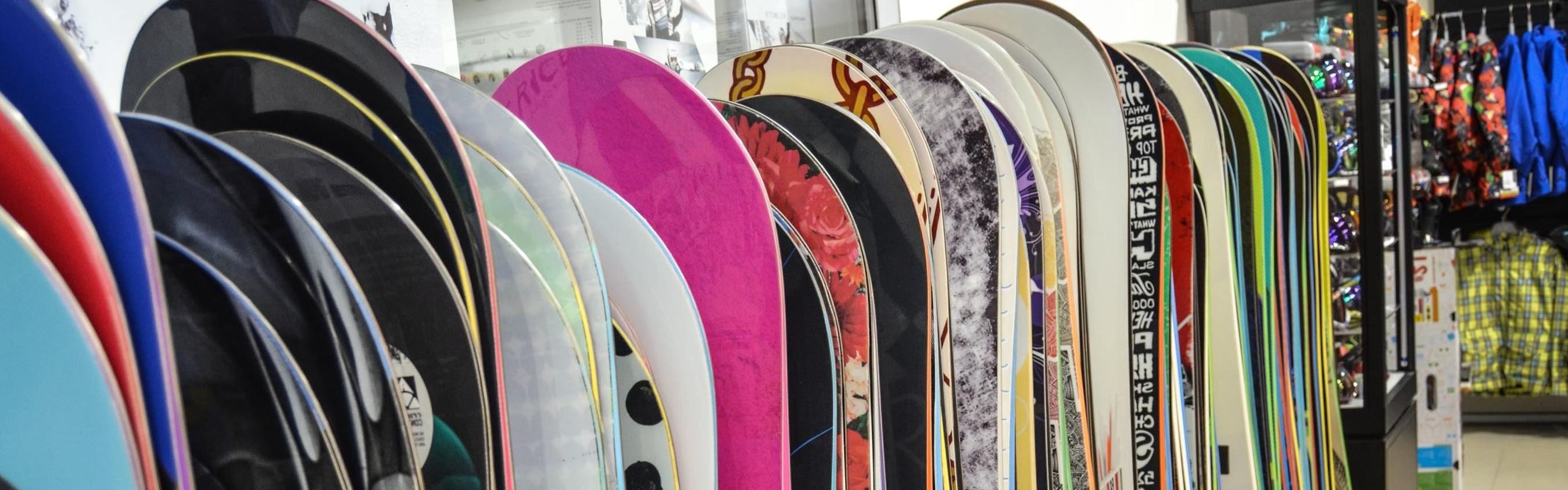 Several snowboards in a line at a store.