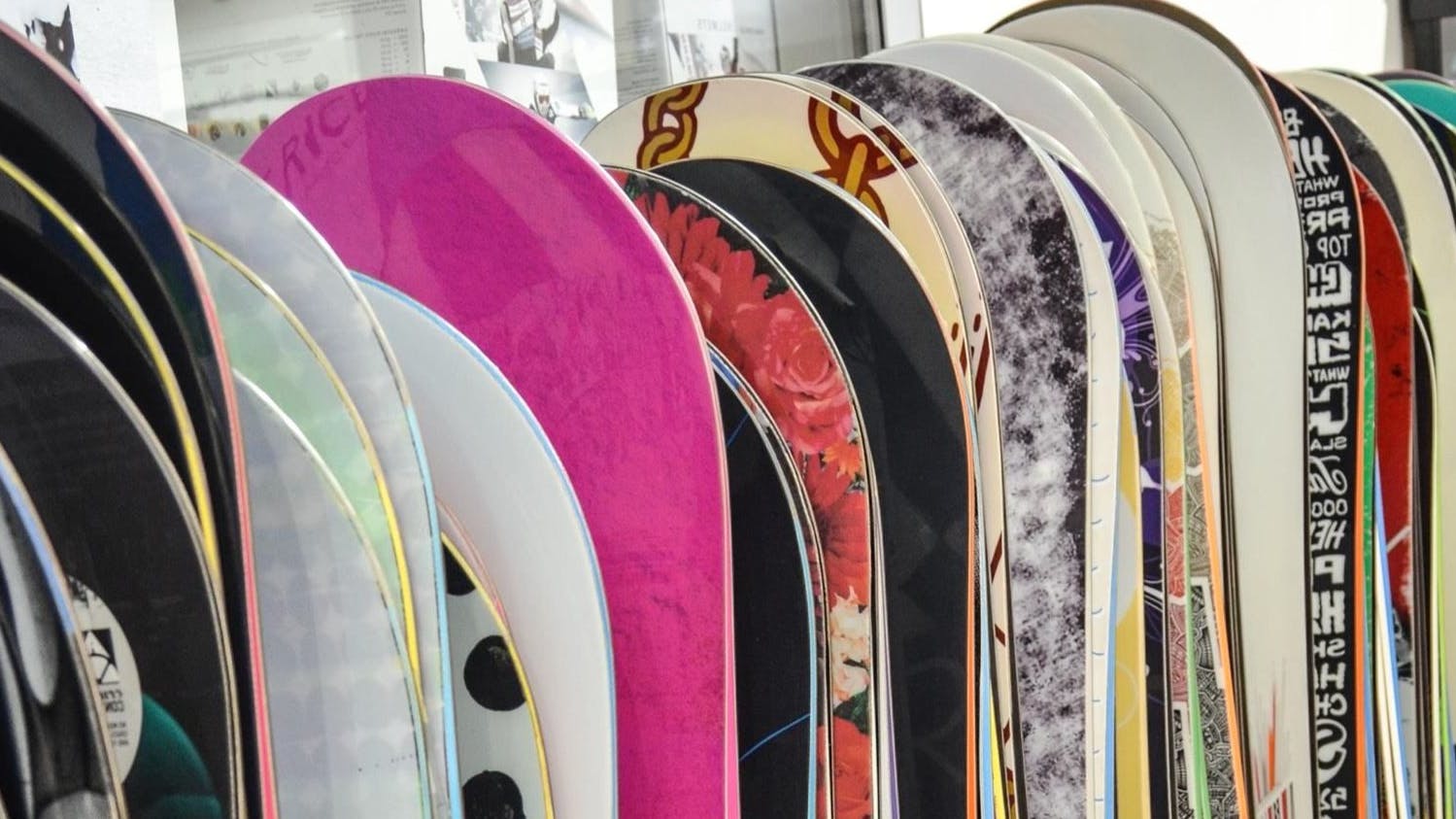Several snowboards in a line at a store.
