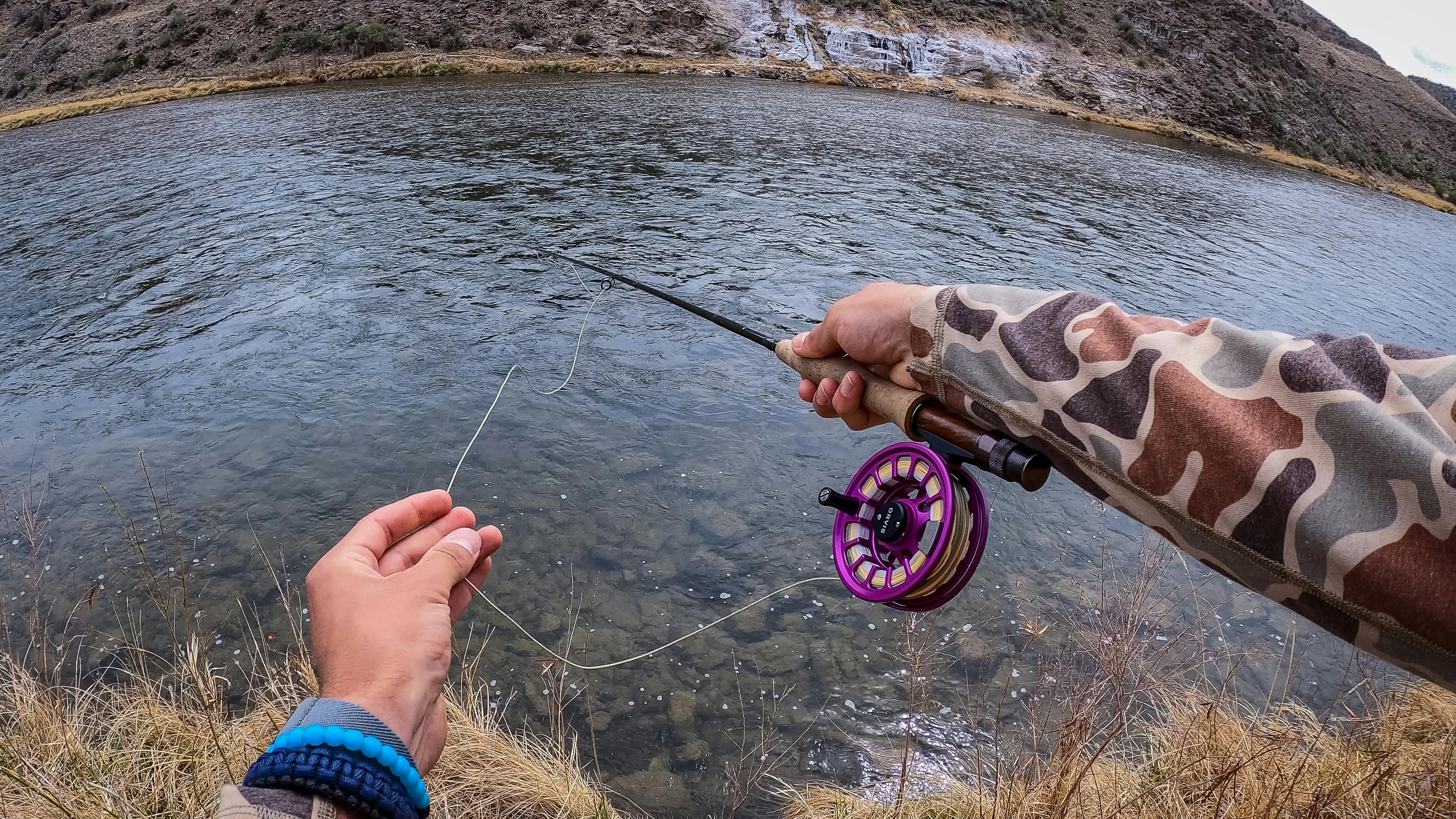 View of someone fishing with the Orvis Recon fly rod. They are using one hand to pull line out and one hand to hold the rod. 