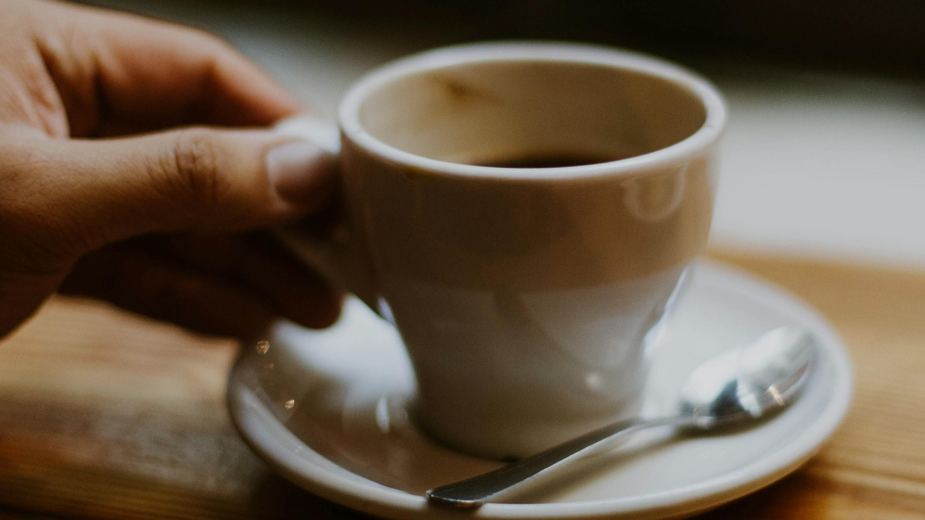 A hand holding a cup of espresso. 