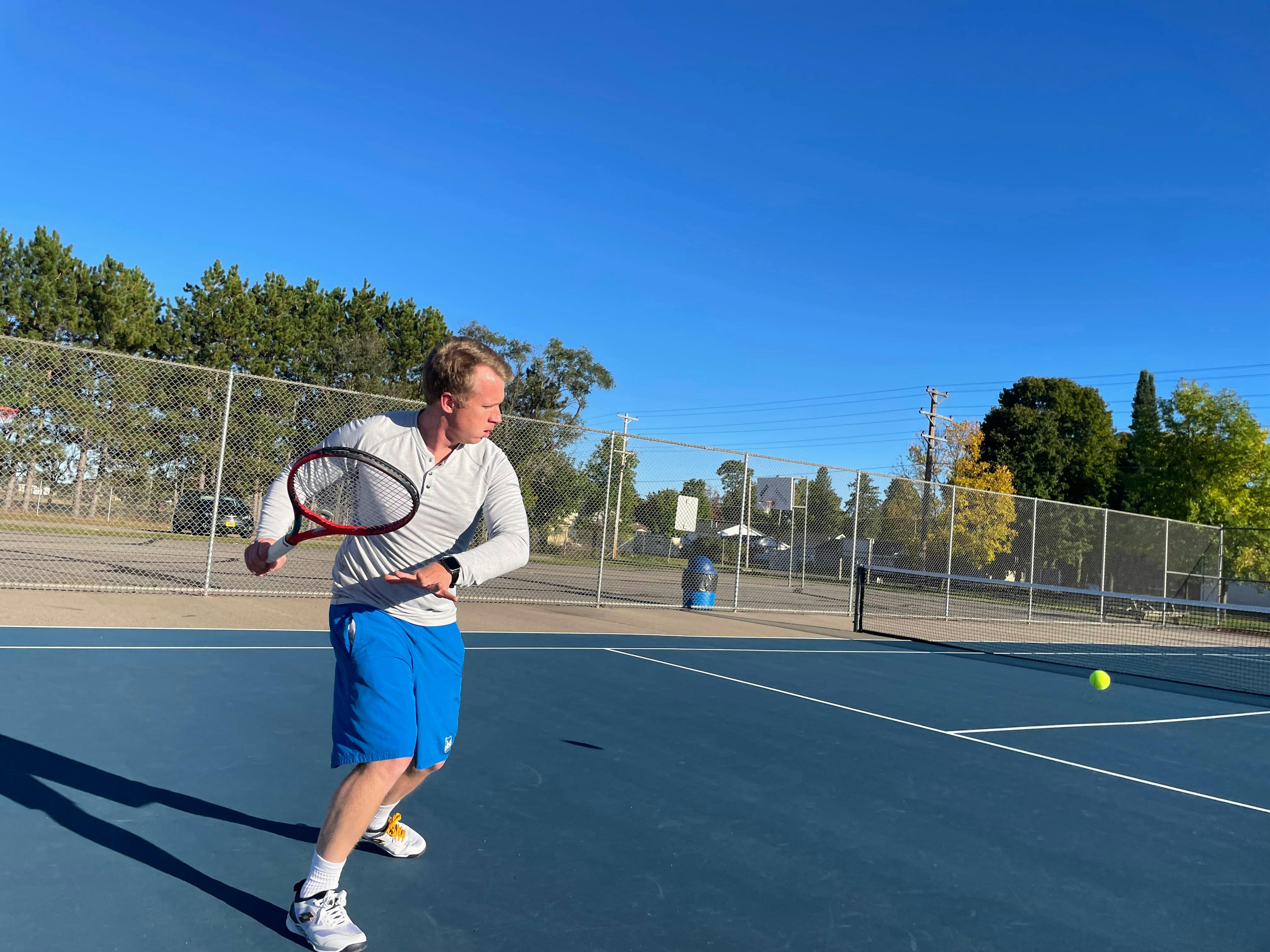 A man playing tennis with the Yonex VCore 100 Racquet. 