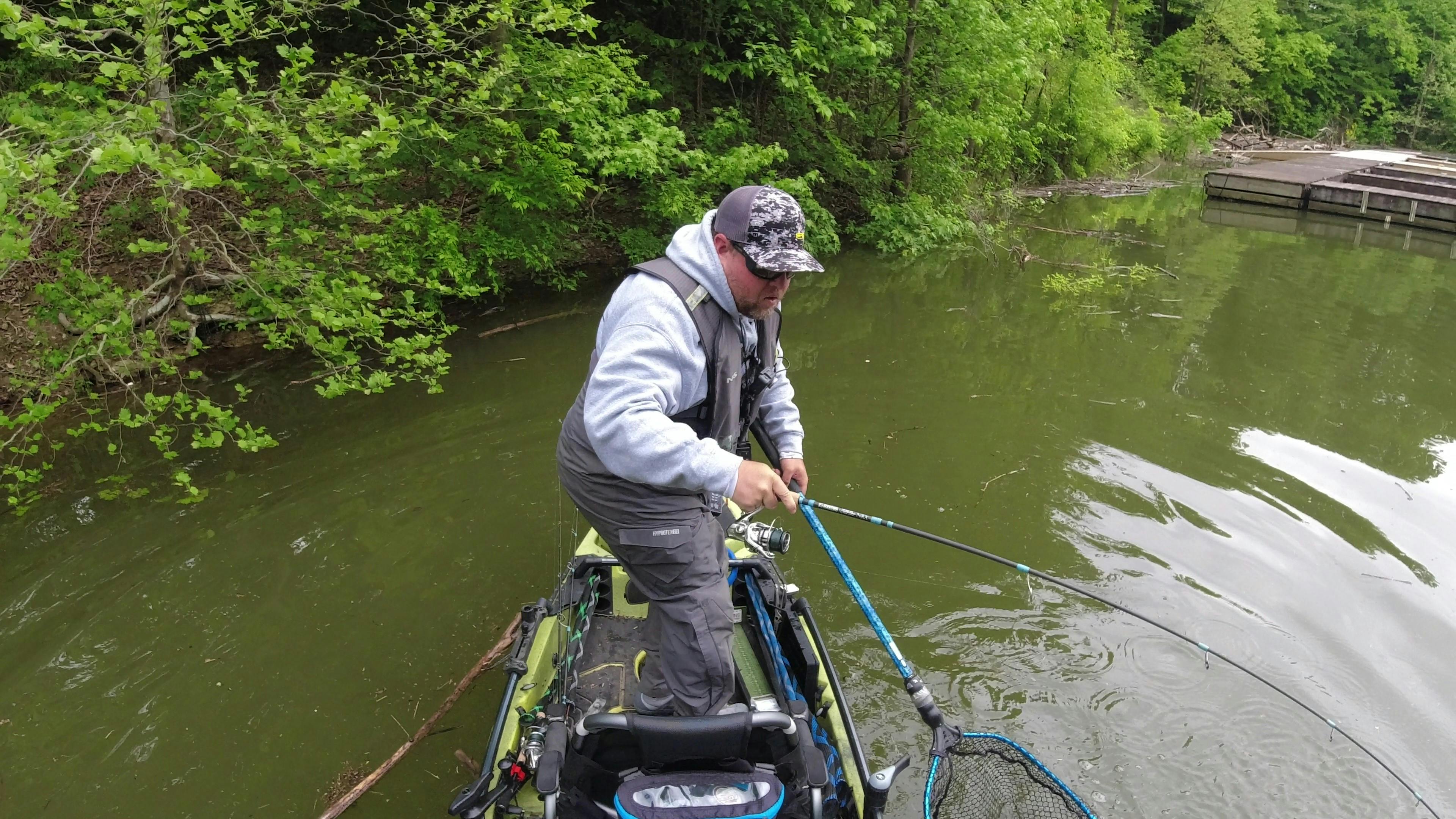 A man using the Shimano Stradic FL Spinning Reel for fishing while on a kayak in a river.