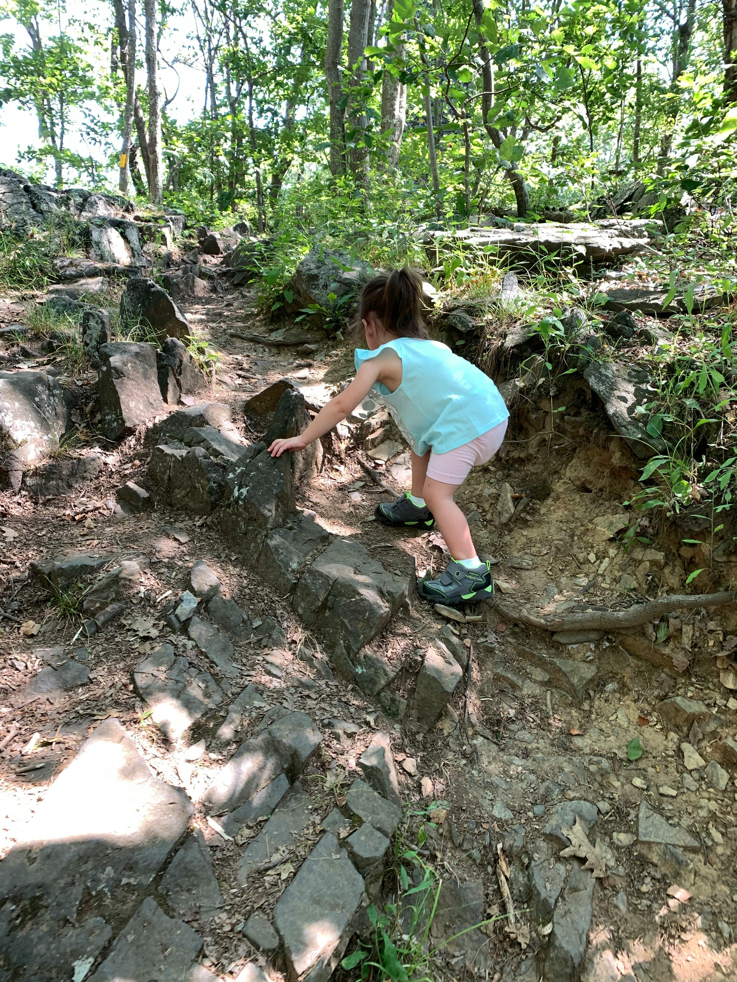 A little girl clambers up rocks