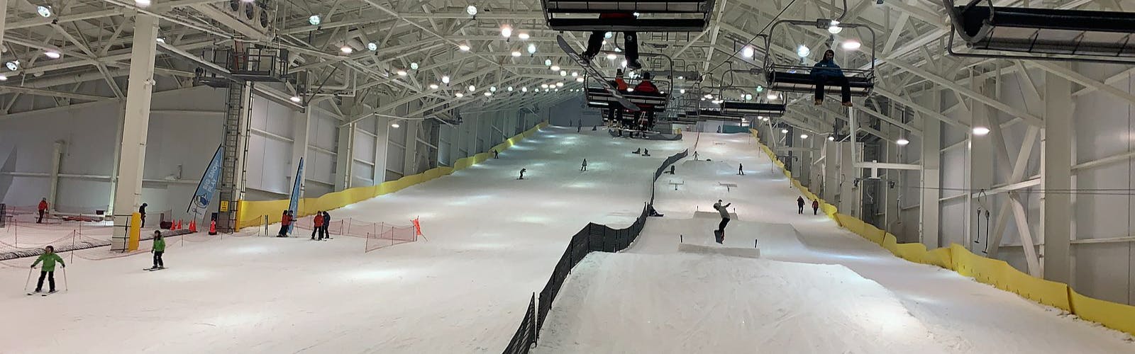 People ride a charilift at an indoor ski facility. 