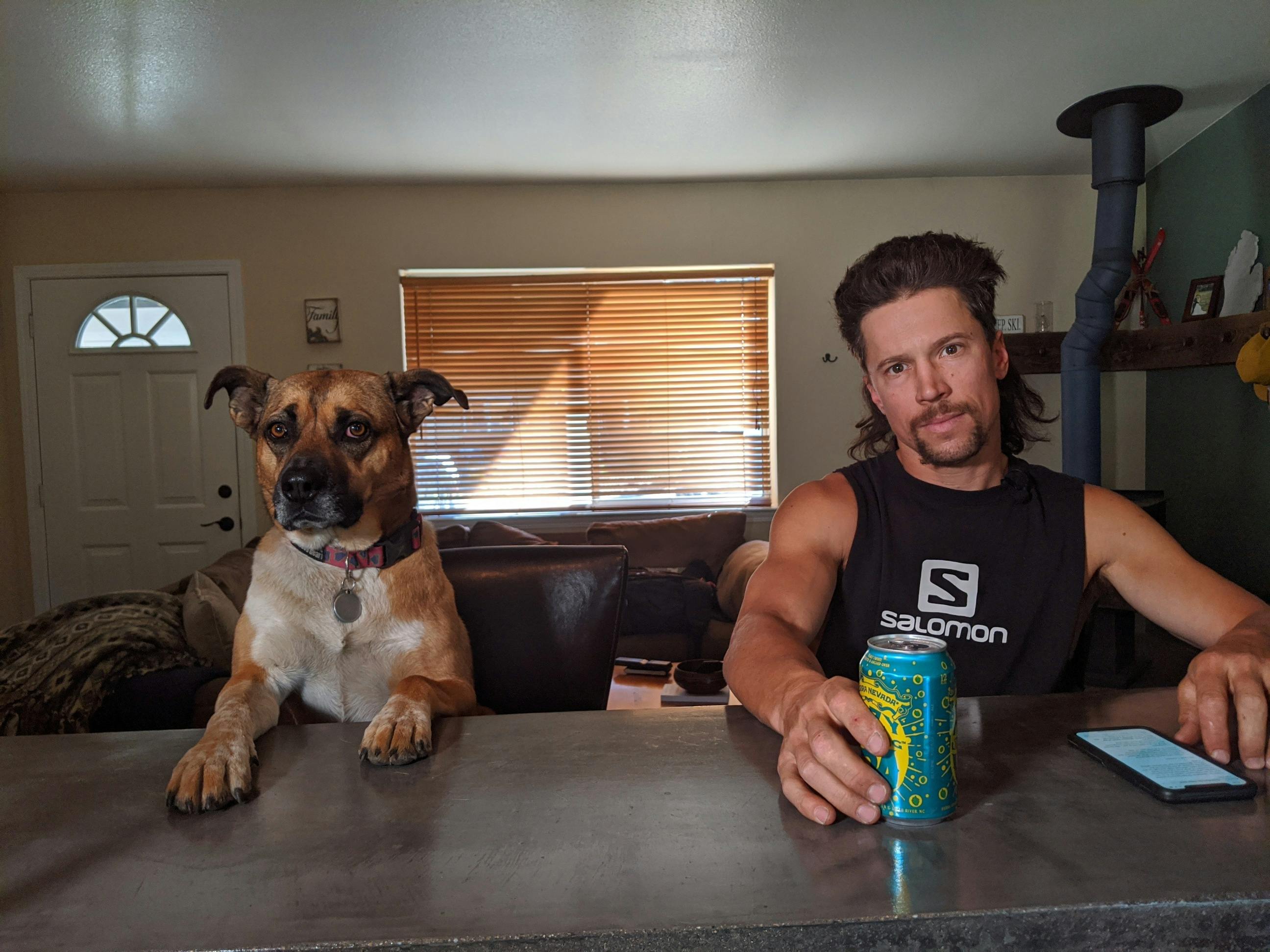 Josh and his dog sit at a counter and look at the camera. 