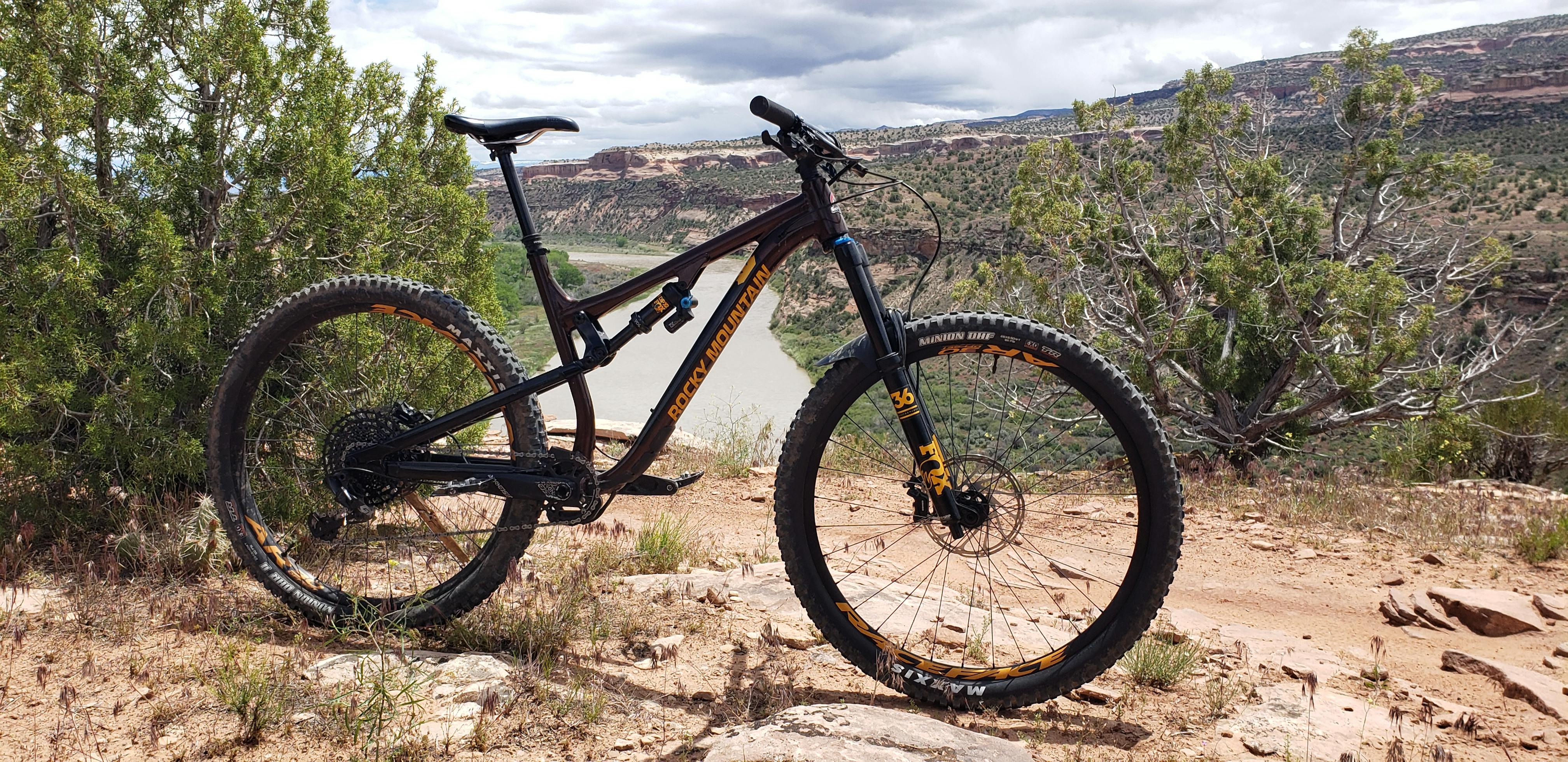 A mountain bike standing on the edge of a cliff with a river in the background