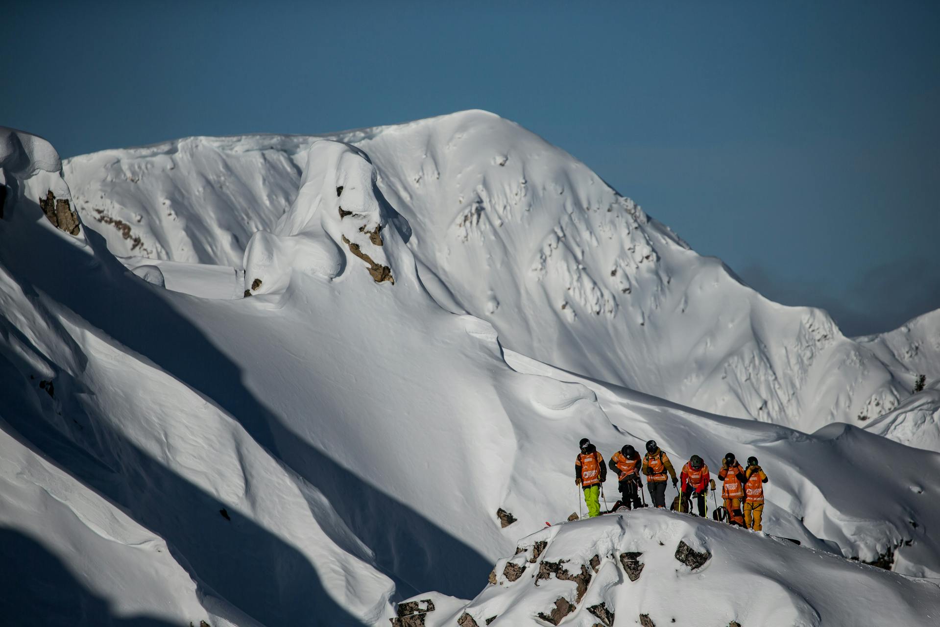 A group of skiers gathers on a mountaintop. 