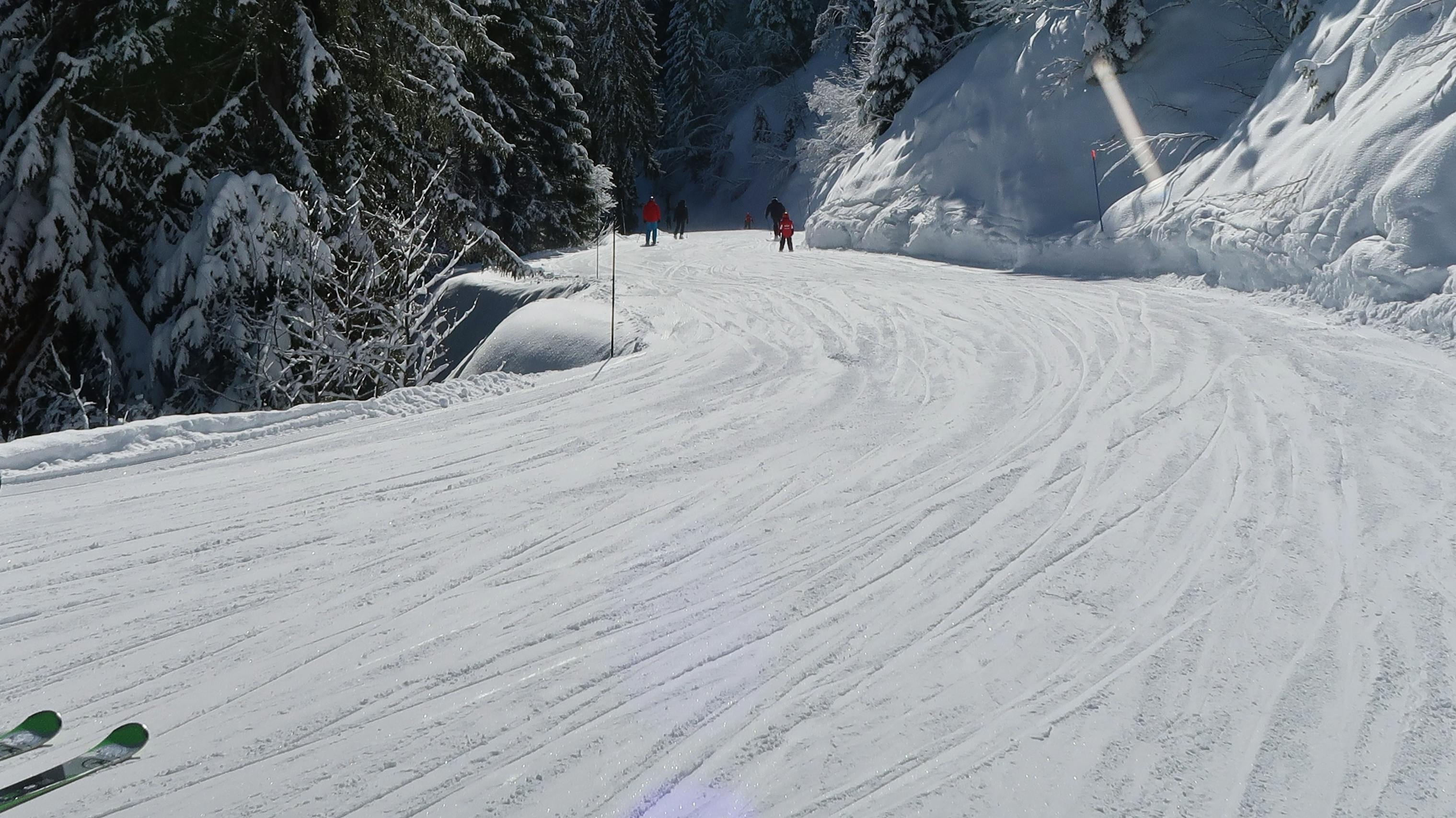 A skier on a groomed run wearing a backpack and helmet.