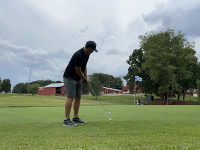 A man takes a swing with a putter.