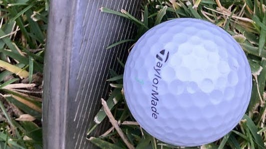 A TaylorMade Kalea Golf Balls in front of a golf club. 
