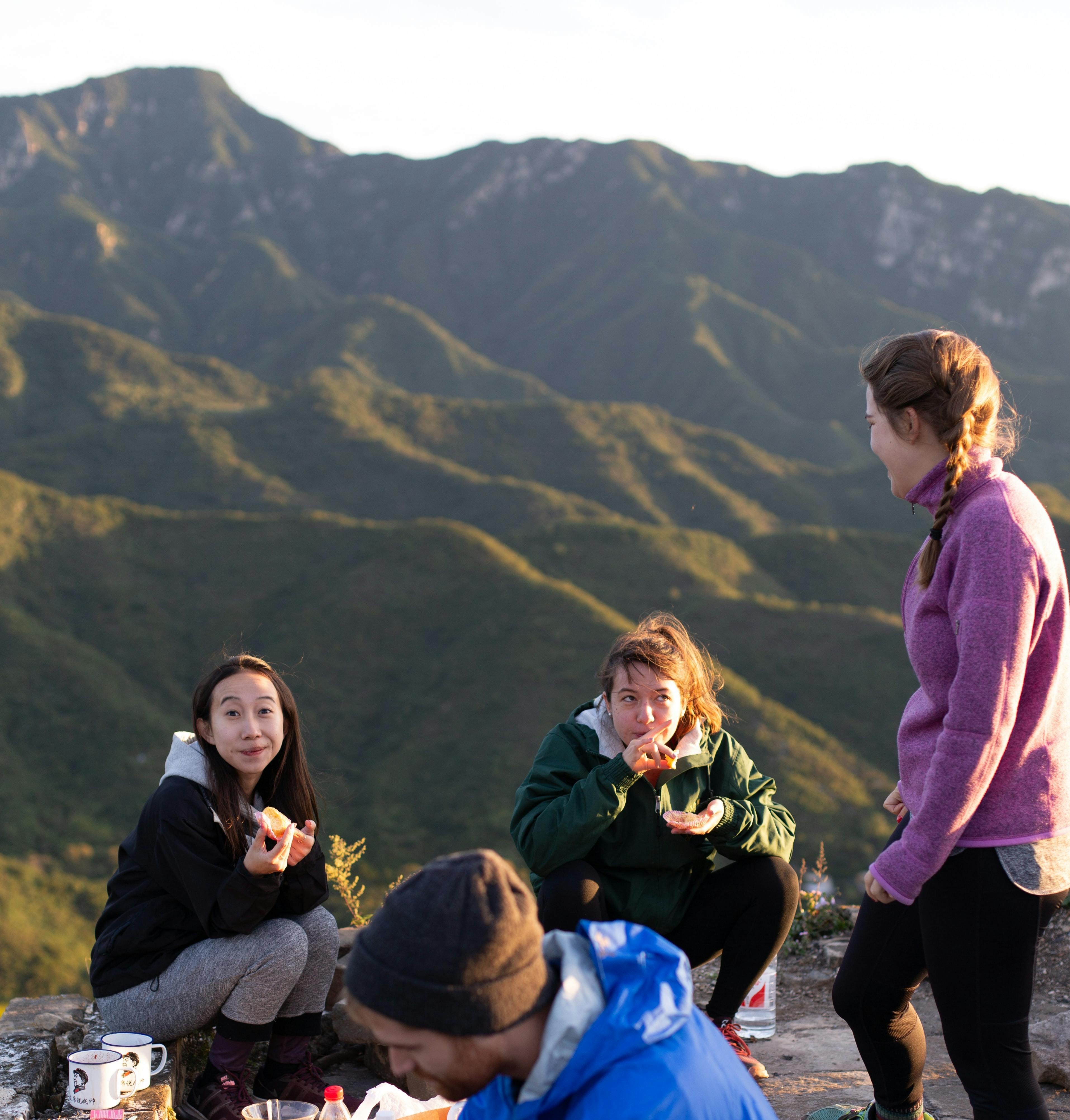 Four people outside eating with some mountains in the background.