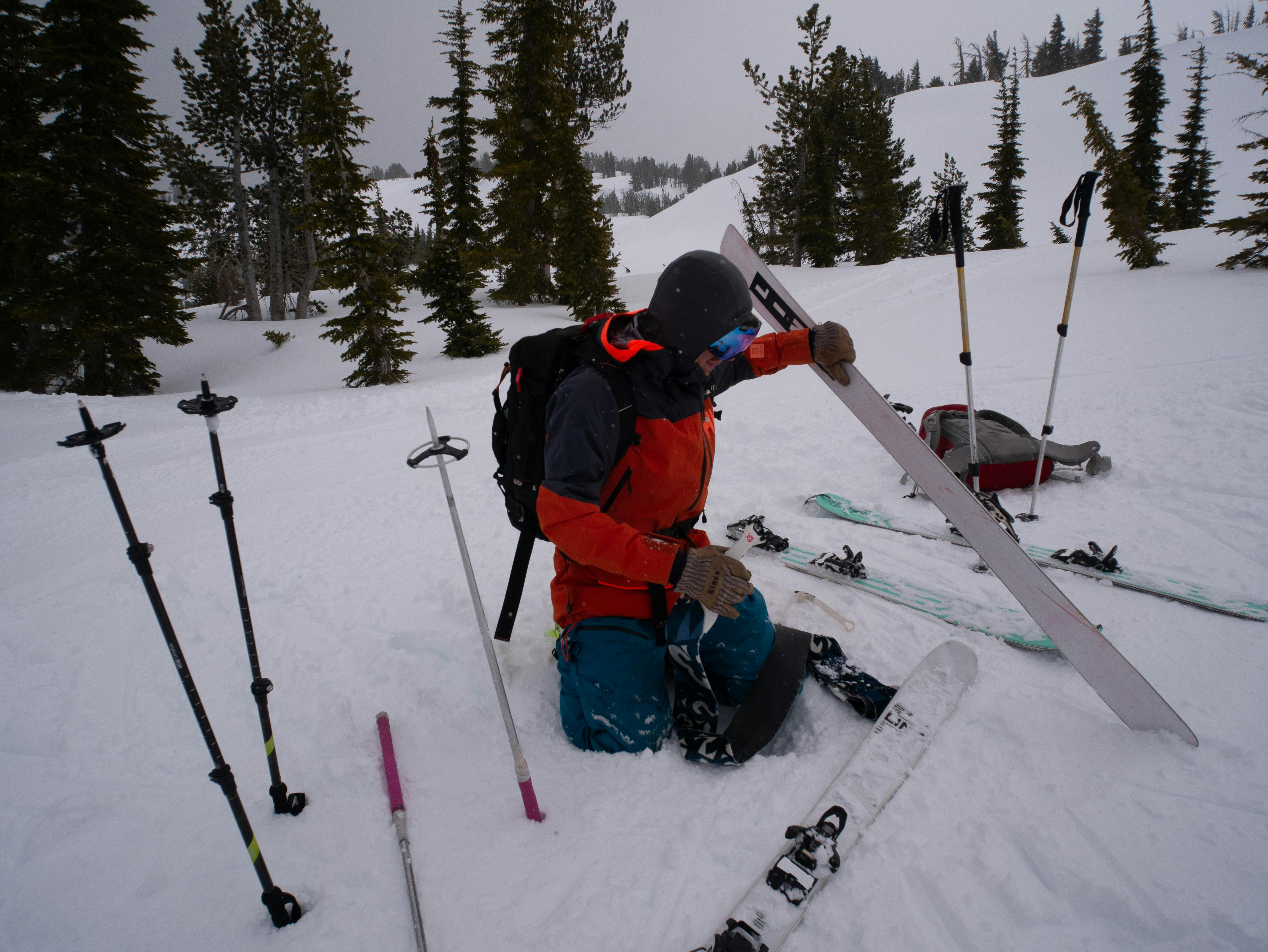 A skier sitting next to his skis in a snowy meadow. 