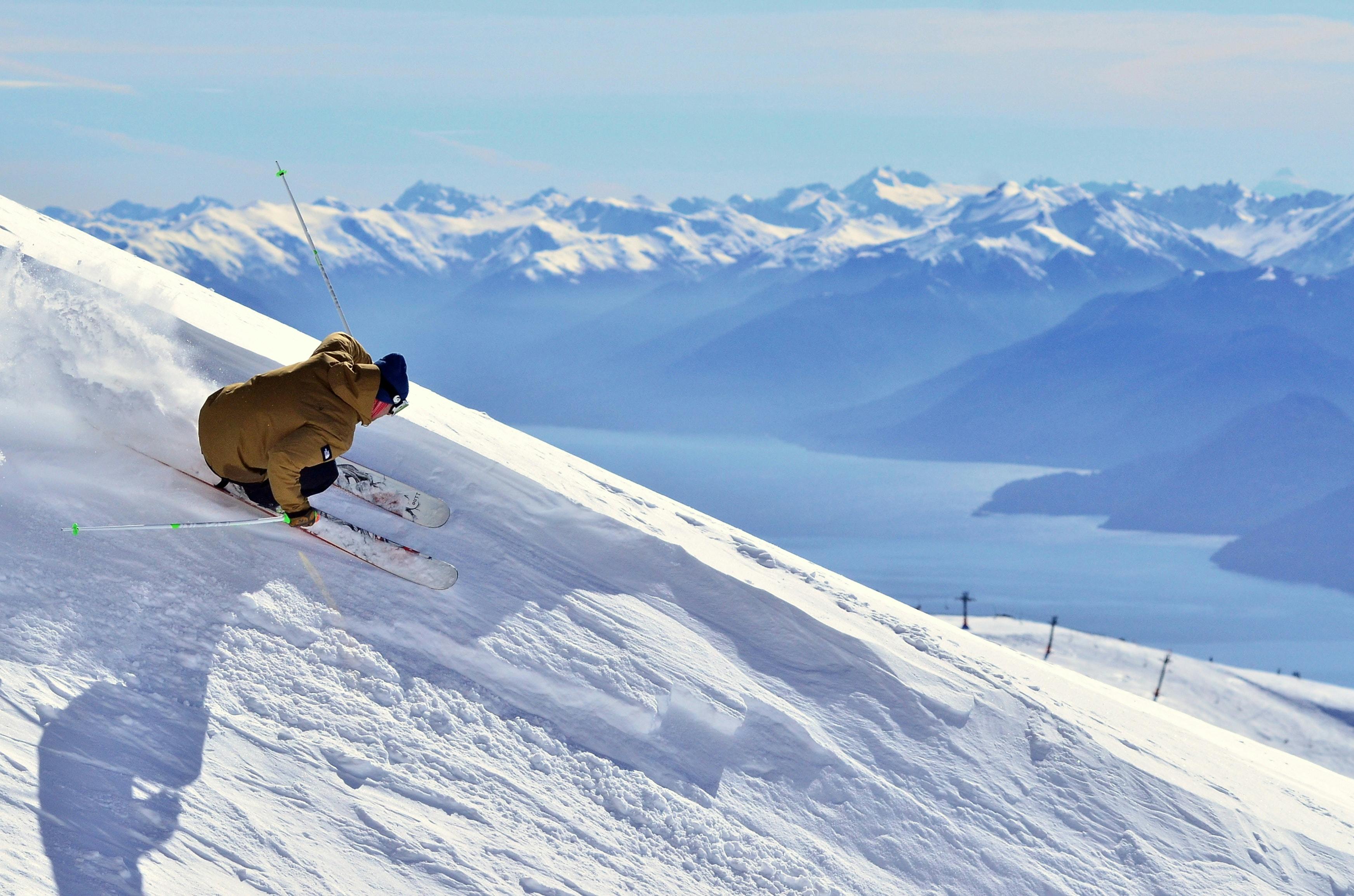 A skier turns on a steep run overlooking mountains
