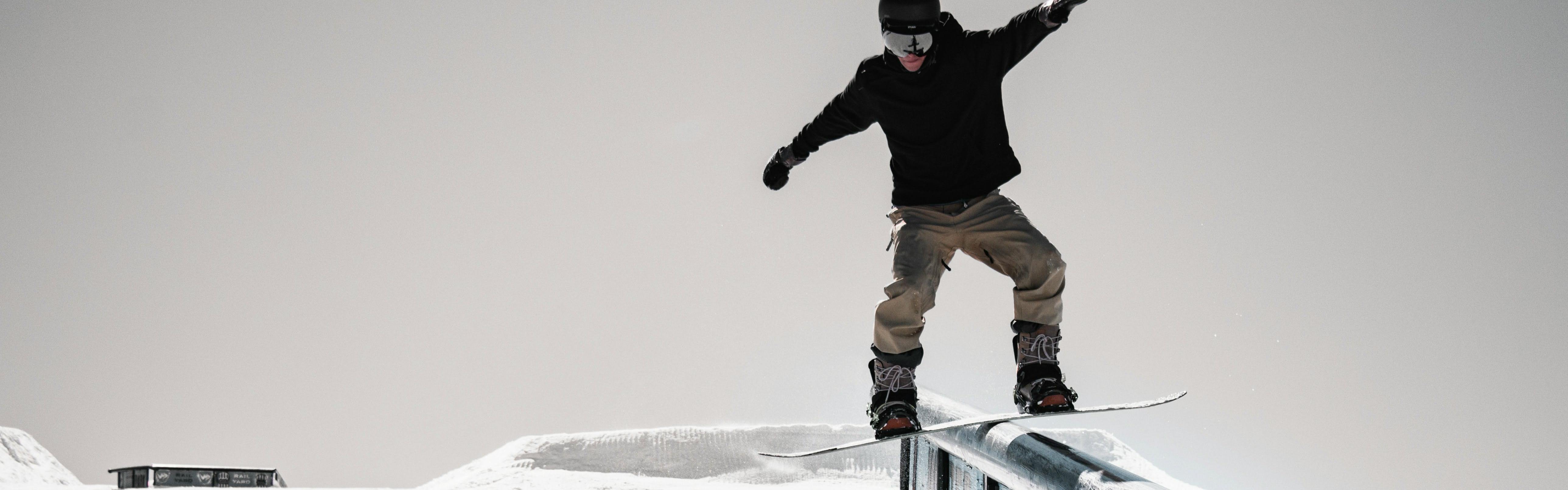 A snowboarder hitting a rail feature. 