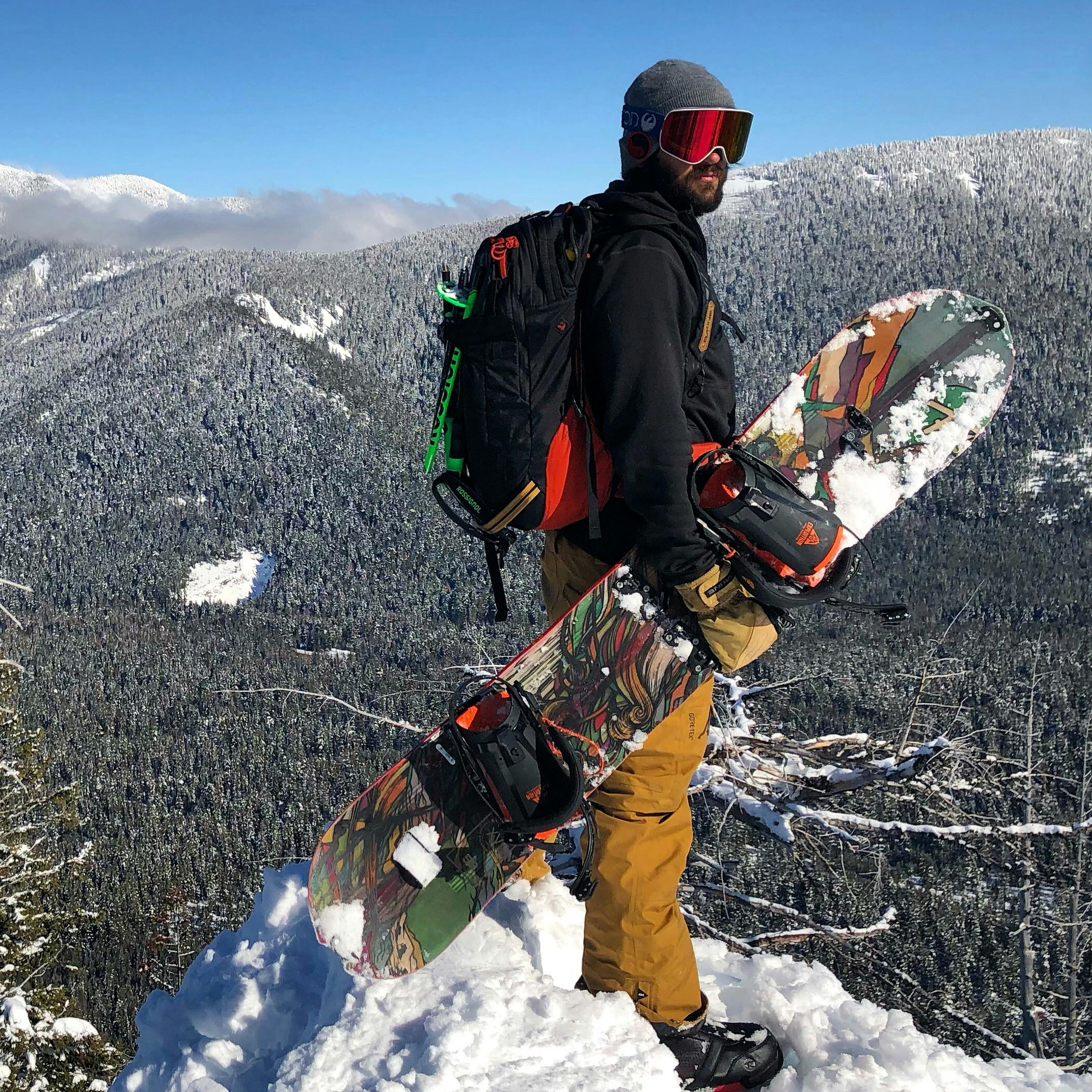 A snowboarder standing at the top of a snowy mountain.
