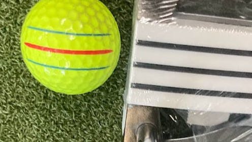The Tour Edge HP Black #6 Putter in front of a golf ball. 
