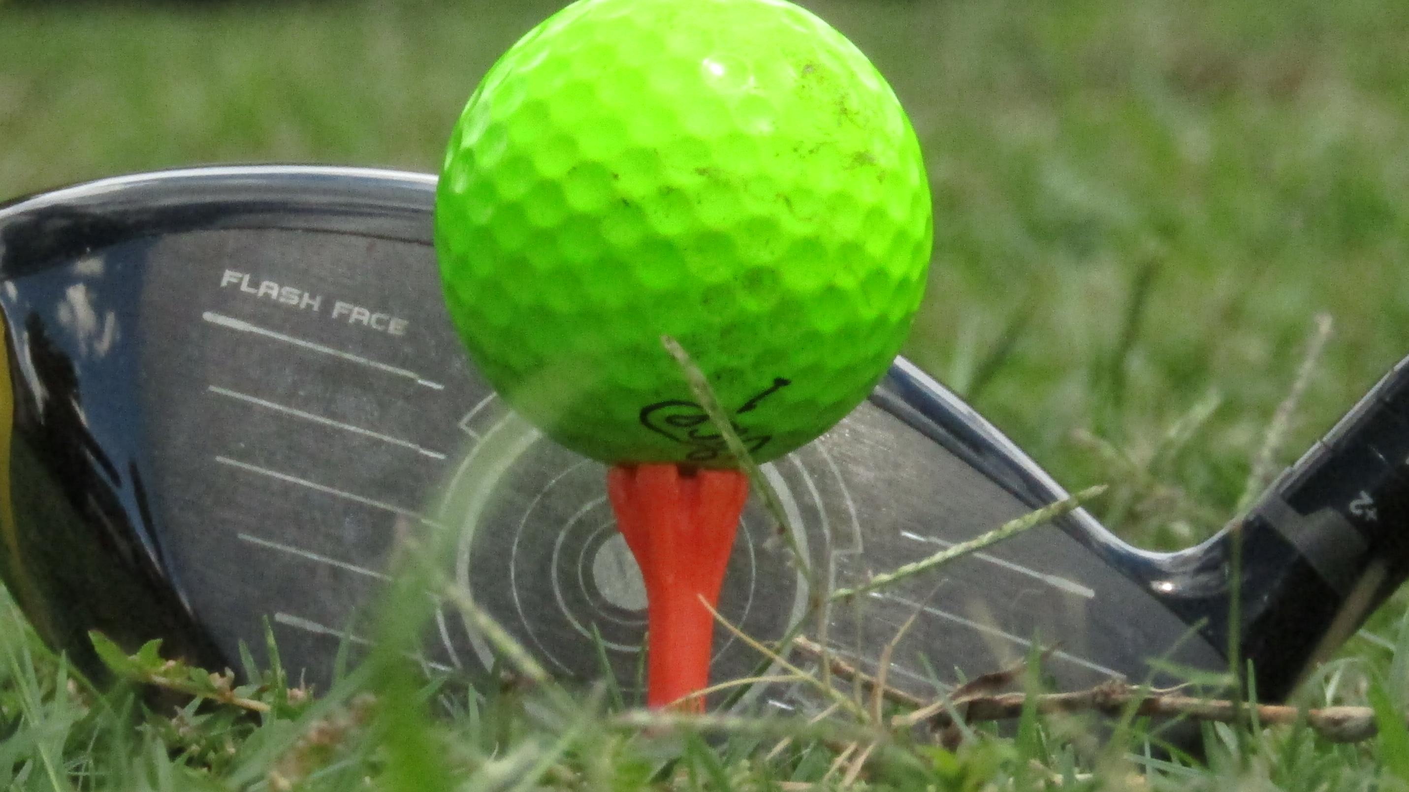 Golf ball on tee with driver behind it
