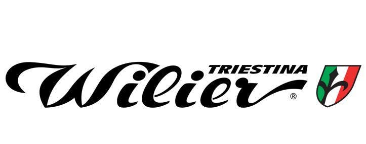 The Wilier Triestina logo reads "Wilier Triestina" with the "Wilier" in a cursive font and the "Triestina" in a block print above it and to the right. On the right is a shield in the colors of an Italian flag. 