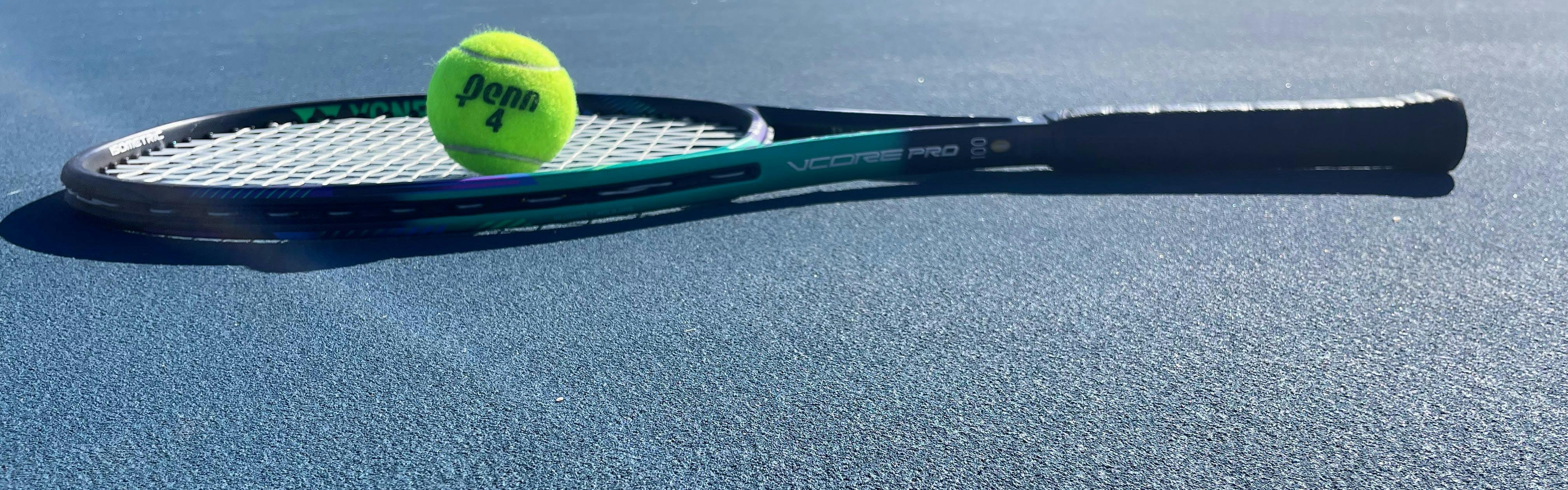 A Yonex VCore Pro 100 Racquet · Unstrung with a tennis ball on it. 