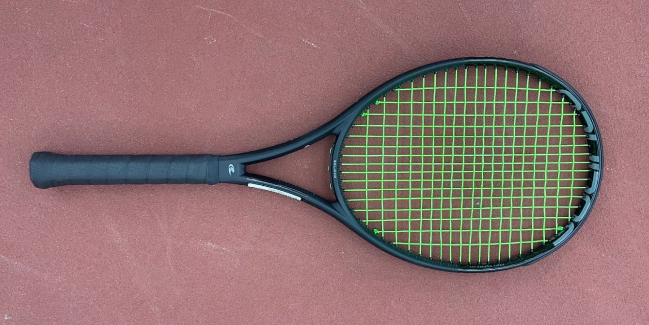 The Solinco Blackout 300 XTD Unstrung Tennis Racquet lying on the ground. 