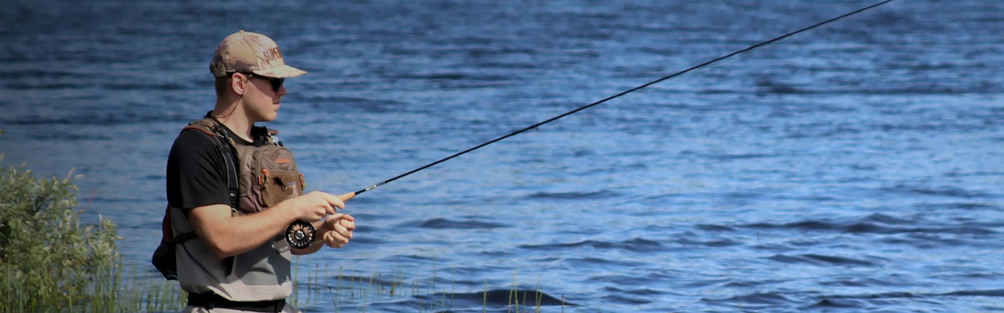 A man standing in a body of water casting a fly rod.