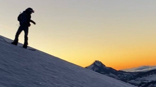 A woman snowboarding down a snowy mountain.