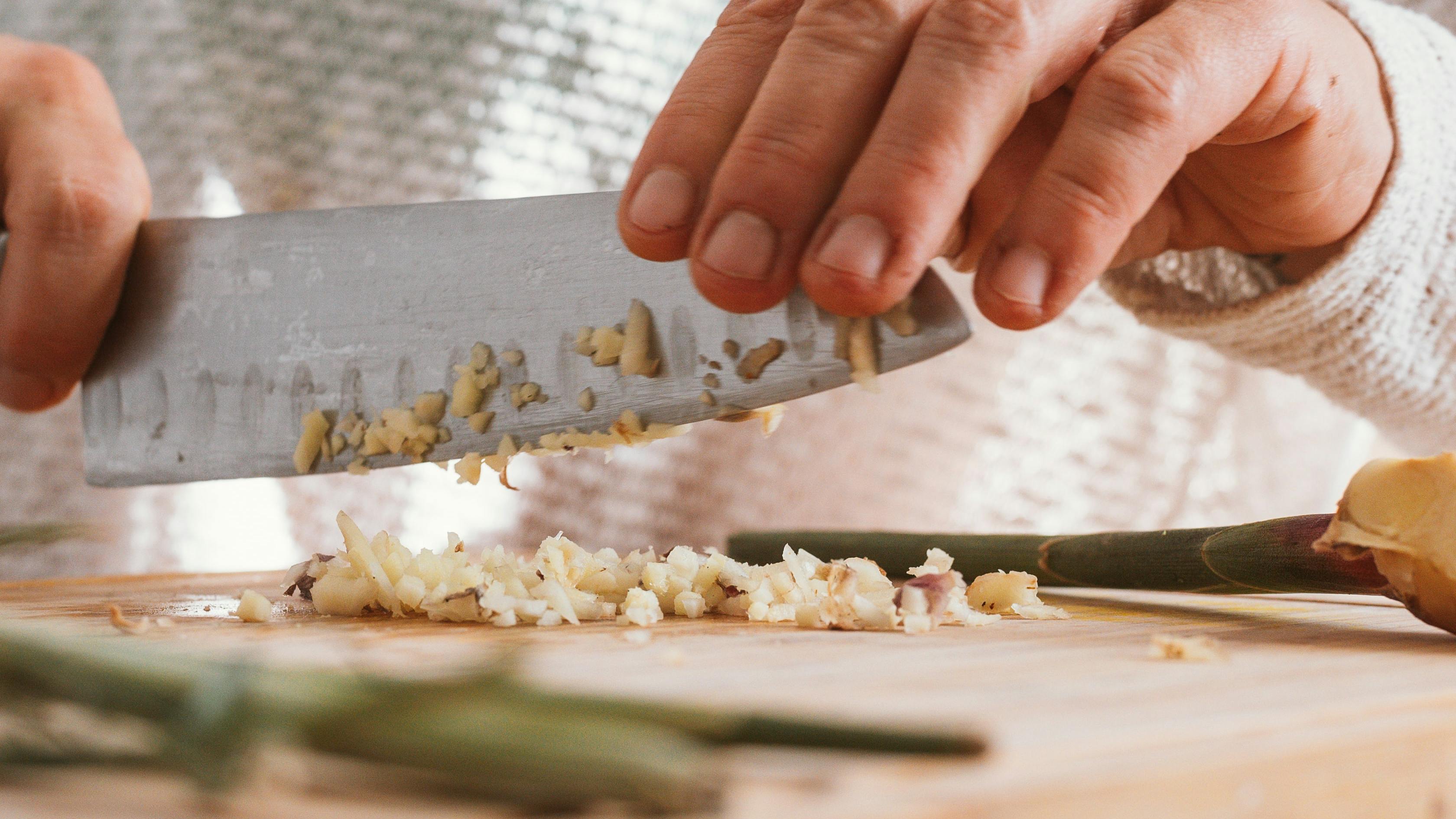 Someone chopping garlic with a knife.