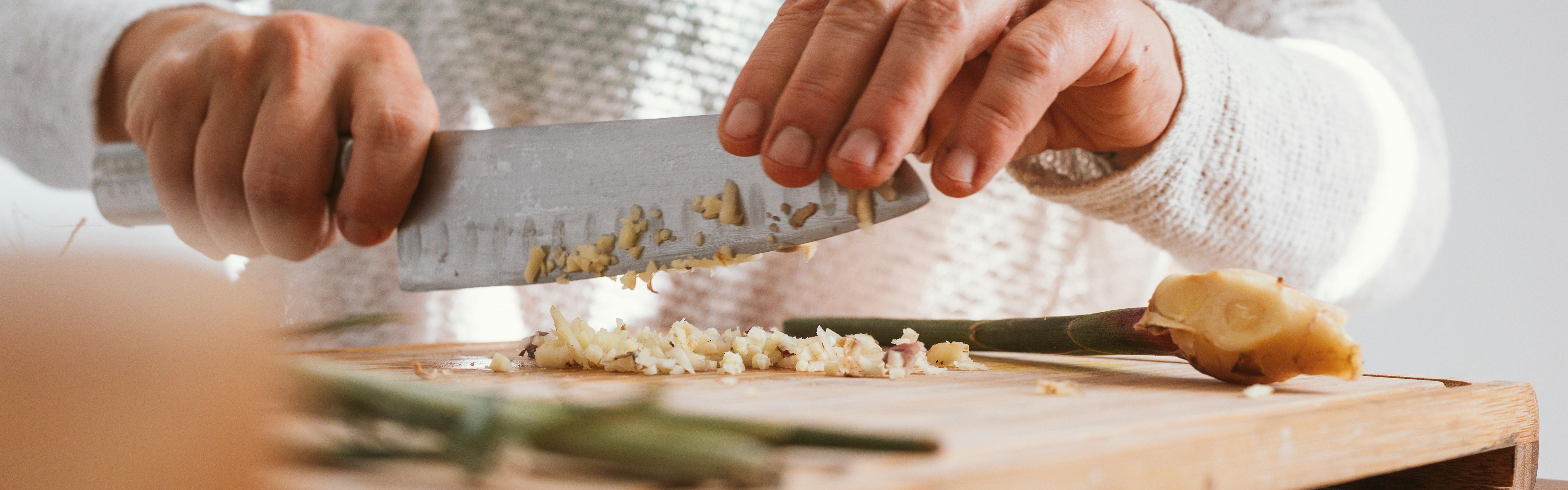 Someone chopping garlic with a knife.