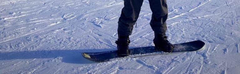 A man standing on the K2 Manifest Snowboard on a snowy run.