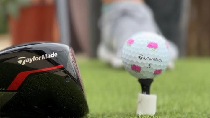 A TaylorMade TP5 Golf Balls in front of a driver. 