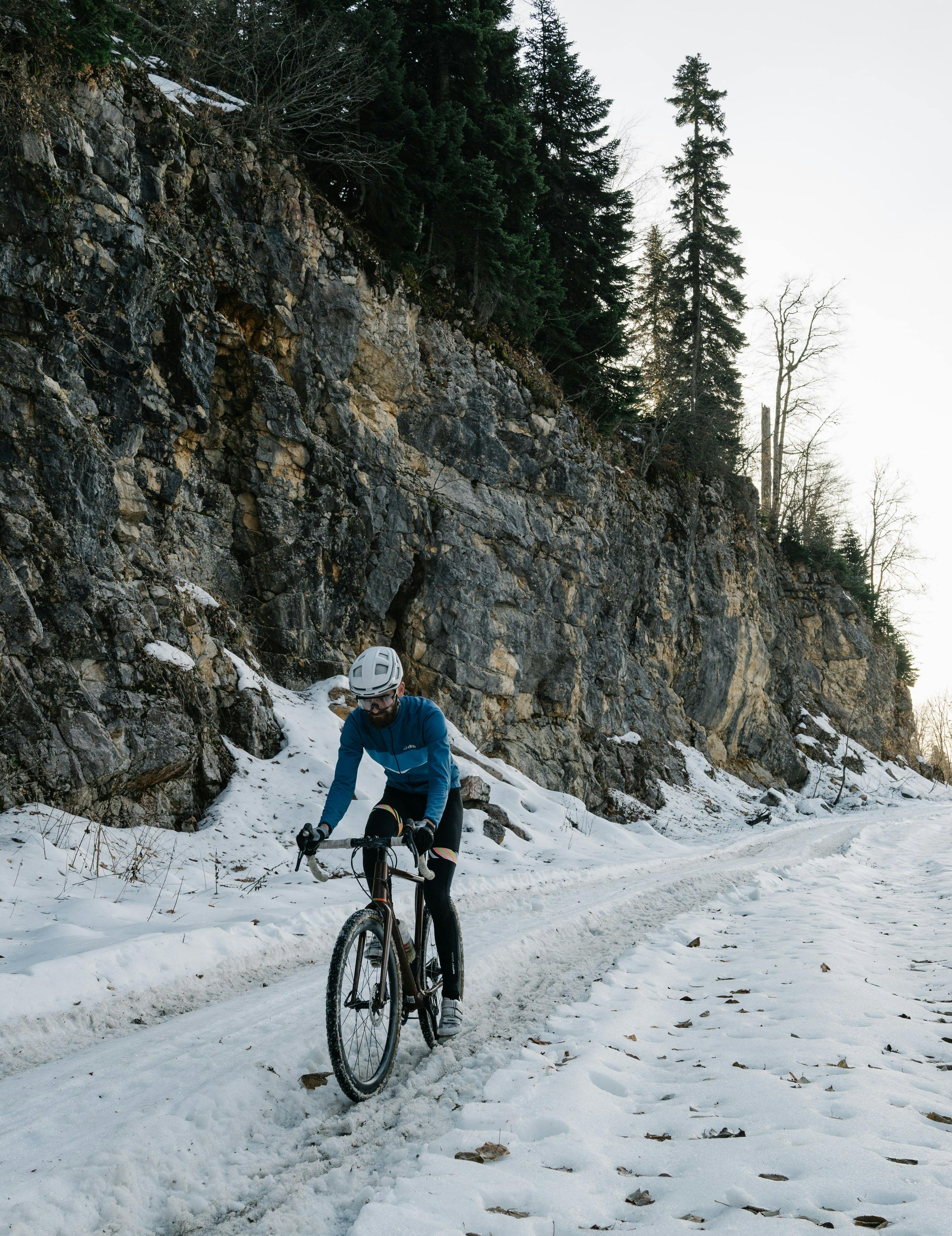 A man cycles on a wide snowy road.